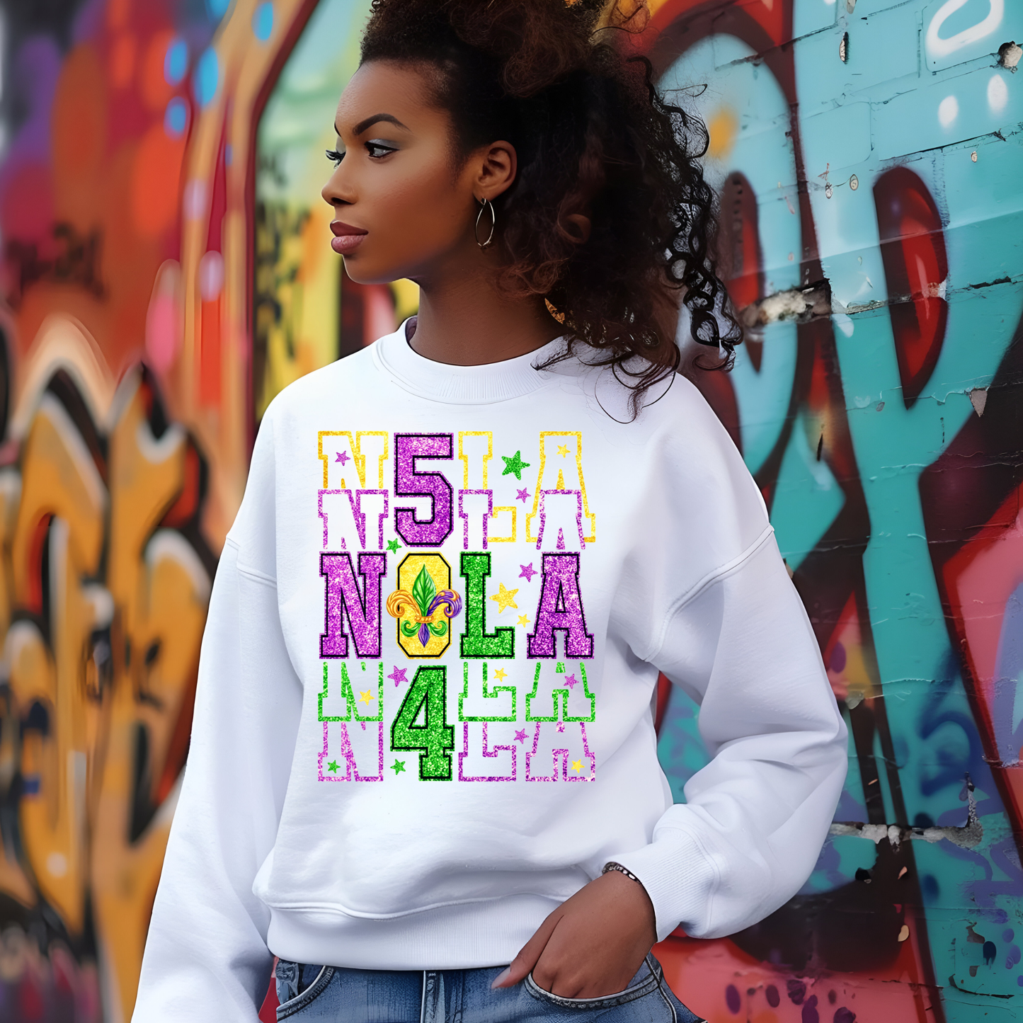 Person wearing a white sweatshirt with colorful text in front of a graffiti-covered wall.
