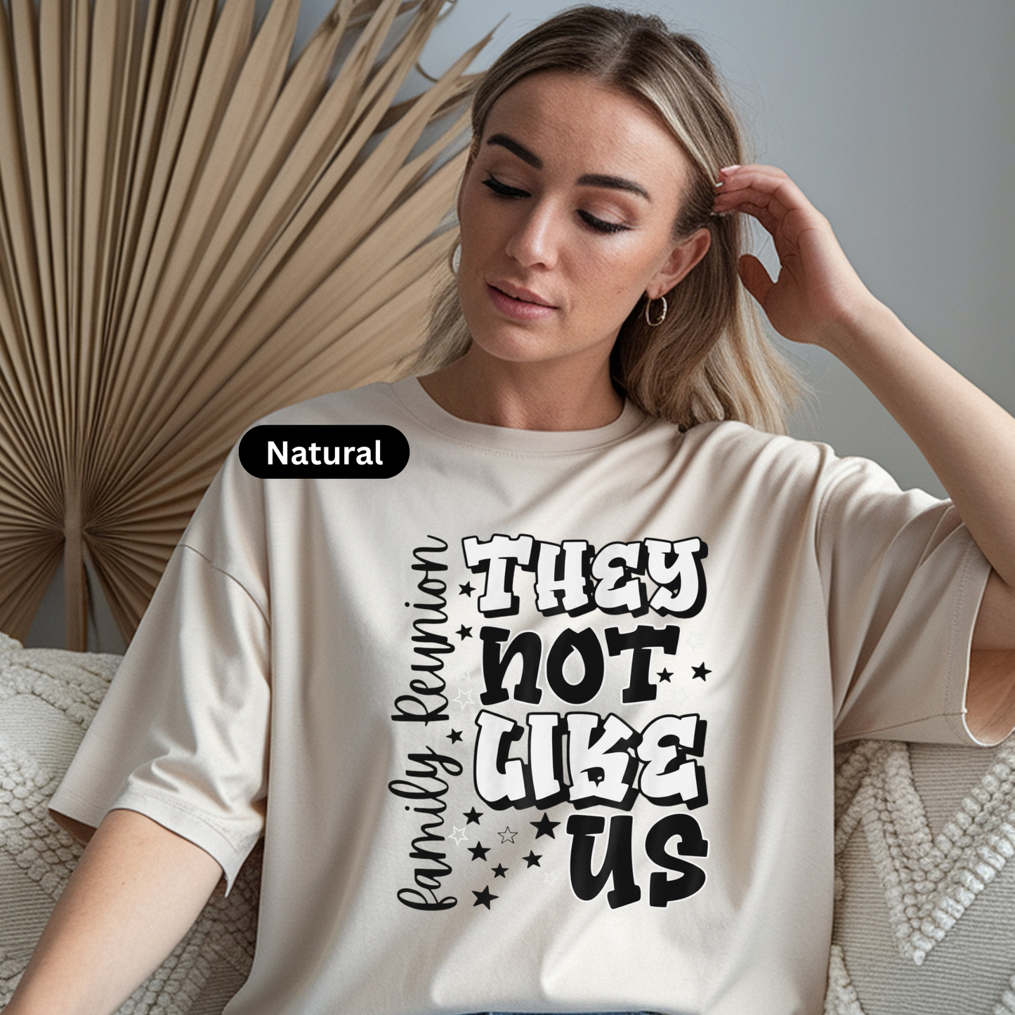 Woman wearing a white t-shirt with text, sitting indoors with decorative elements.