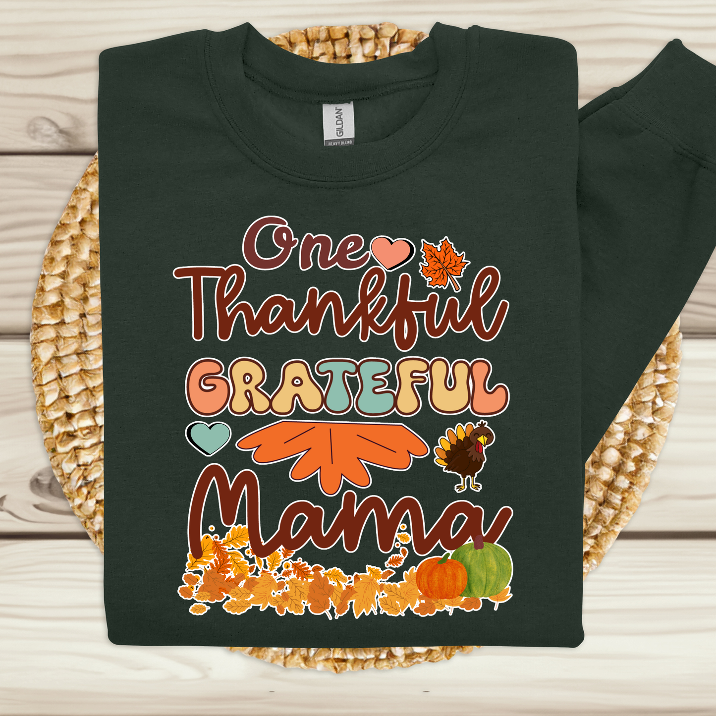 Black sweatshirt with 'One Thankful Grateful Mama' text and fall-themed graphics on a woven mat. Retro Thanksgiving Sweatshirt "One Thankful Mama" Cozy Fall Mom Crewneck