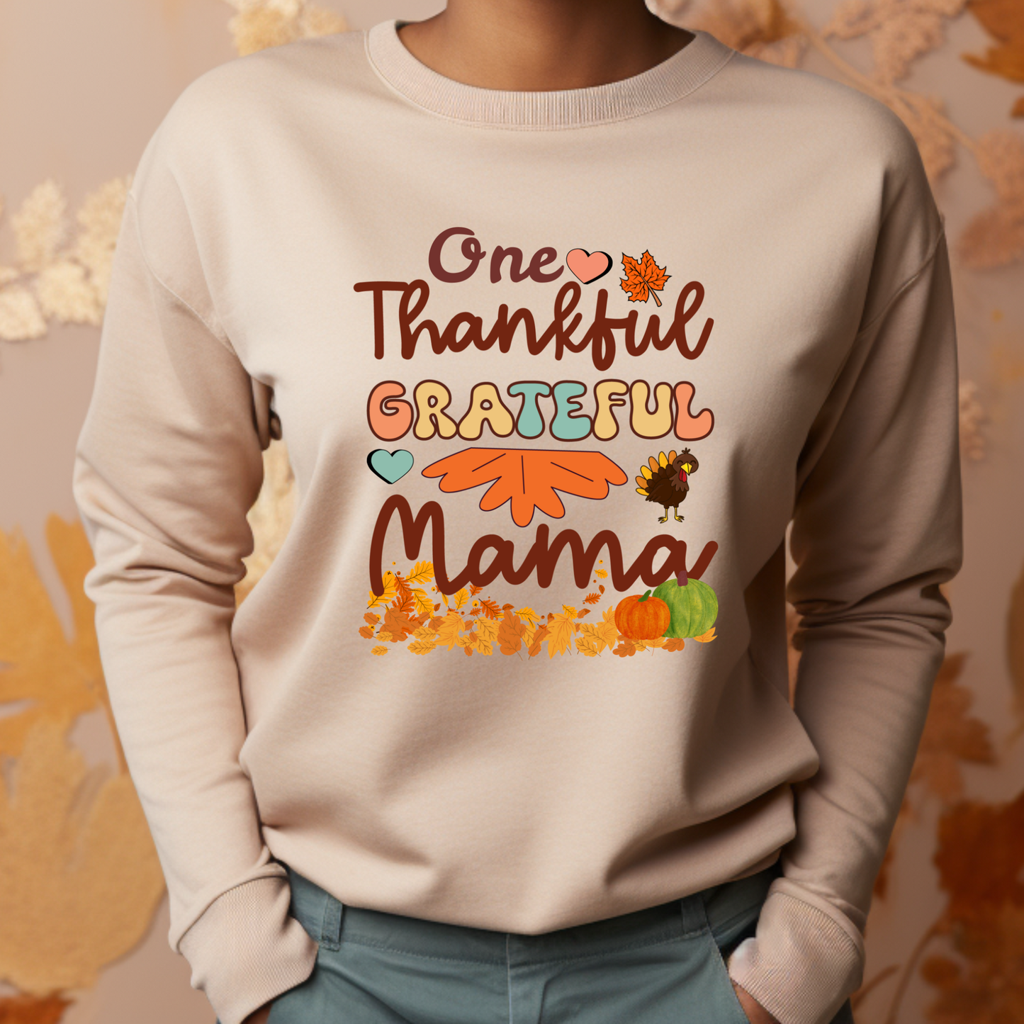Beige sweatshirt with 'One Thankful Grateful Mama' text and fall-themed graphics on a neutral background.  Retro Thanksgiving Sweatshirt "One Thankful Mama" Cozy Fall Mom Crewneck
