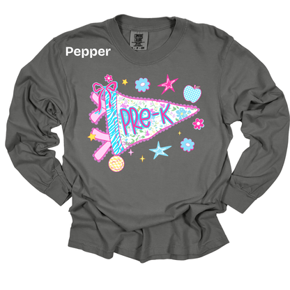 A dark gray long-sleeve t-shirt with a colorful graphic of a pink and blue ribbon pennant that says 'PRE-K' surrounded by stars, flowers, and an apple. The brand name 'Pepper' is printed in white near the left shoulder.