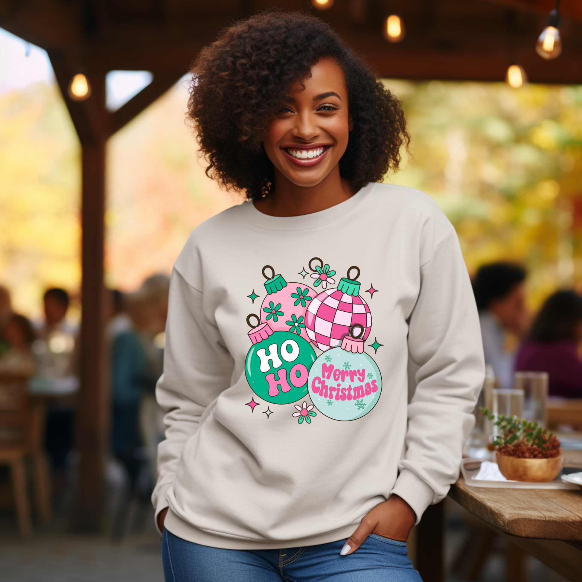 Woman wearing a light gray sweatshirt with Christmas-themed design in an outdoor setting.
