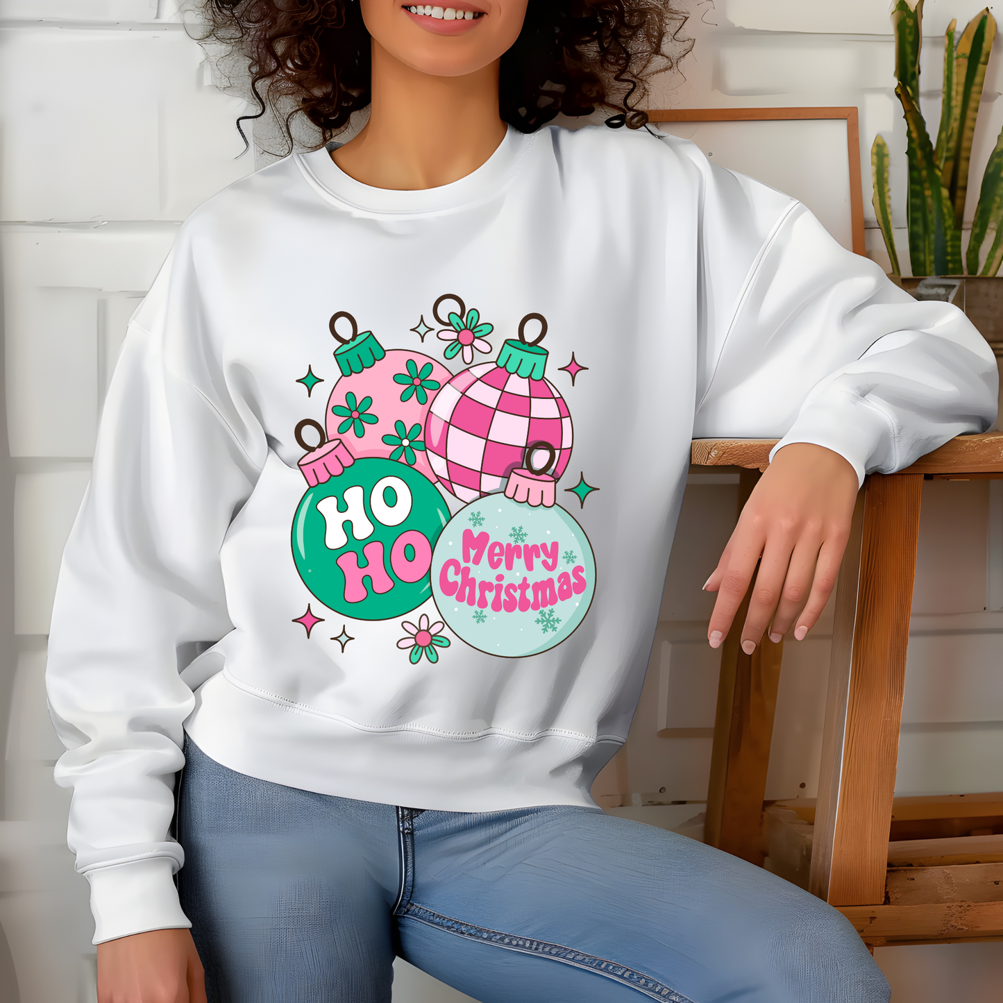 Person wearing a white sweatshirt with Christmas-themed design, sitting on a wooden chair.