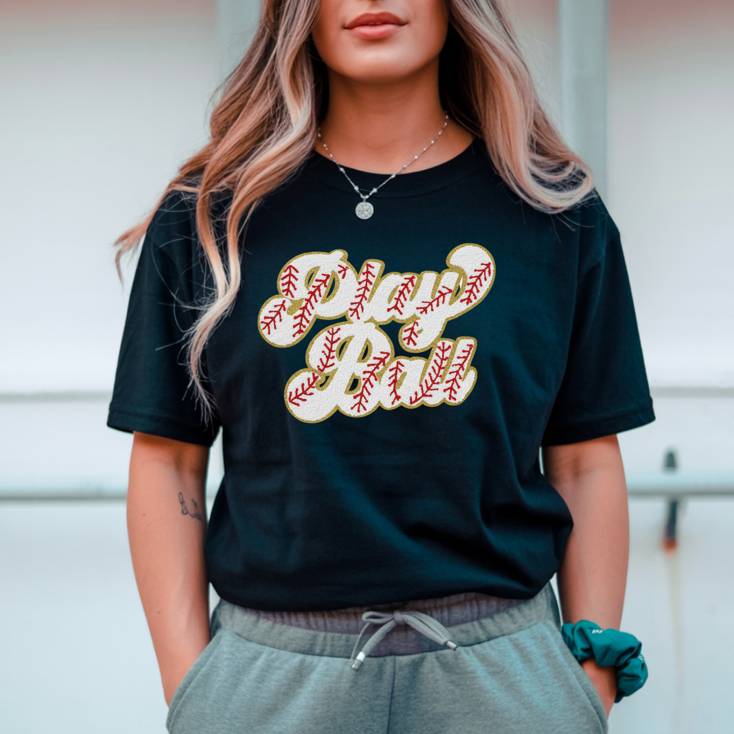 Person wearing a black t-shirt with 'Play Ball' text, standing outdoors.