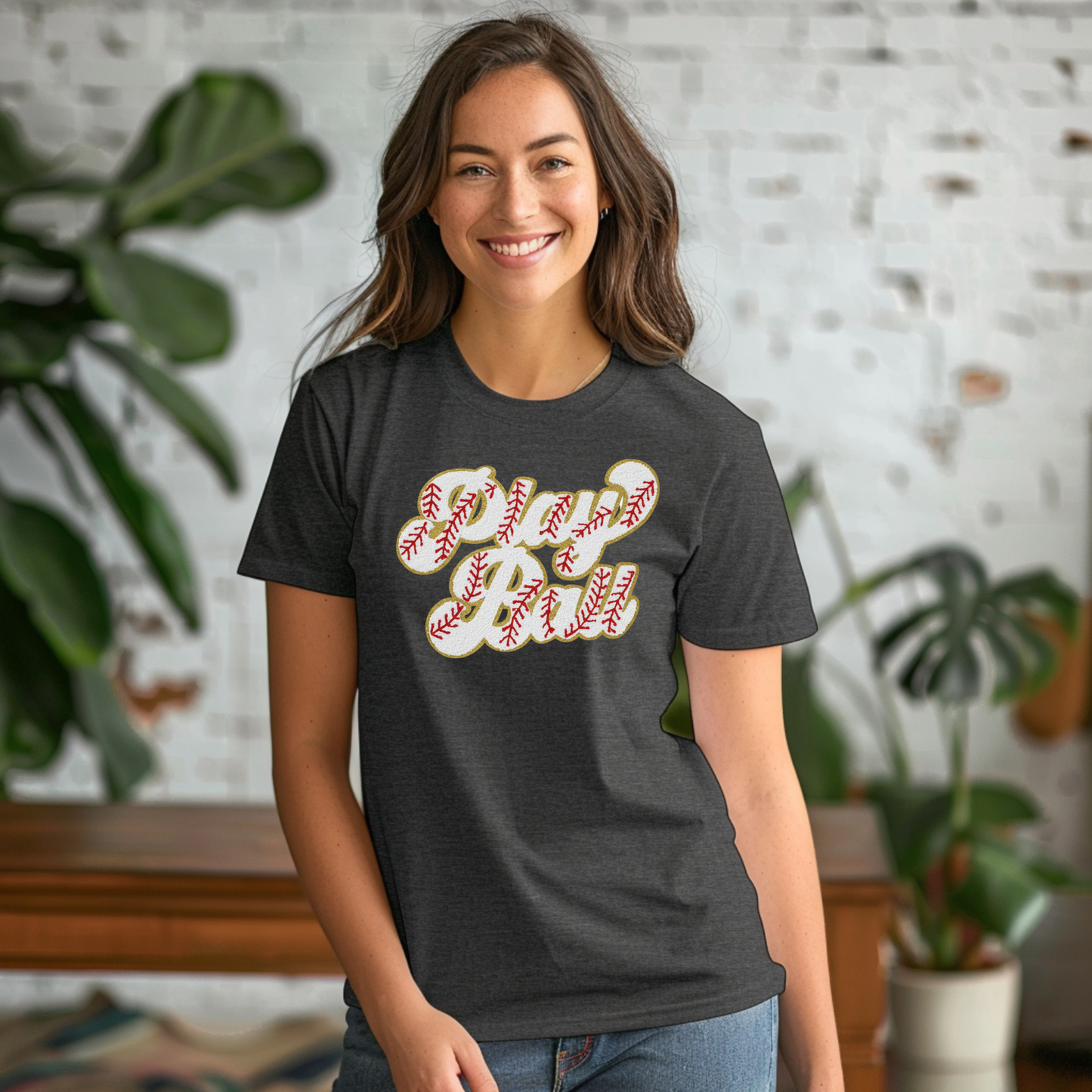 Woman wearing a dark gray t-shirt with a graphic design, standing indoors with plants in the background.