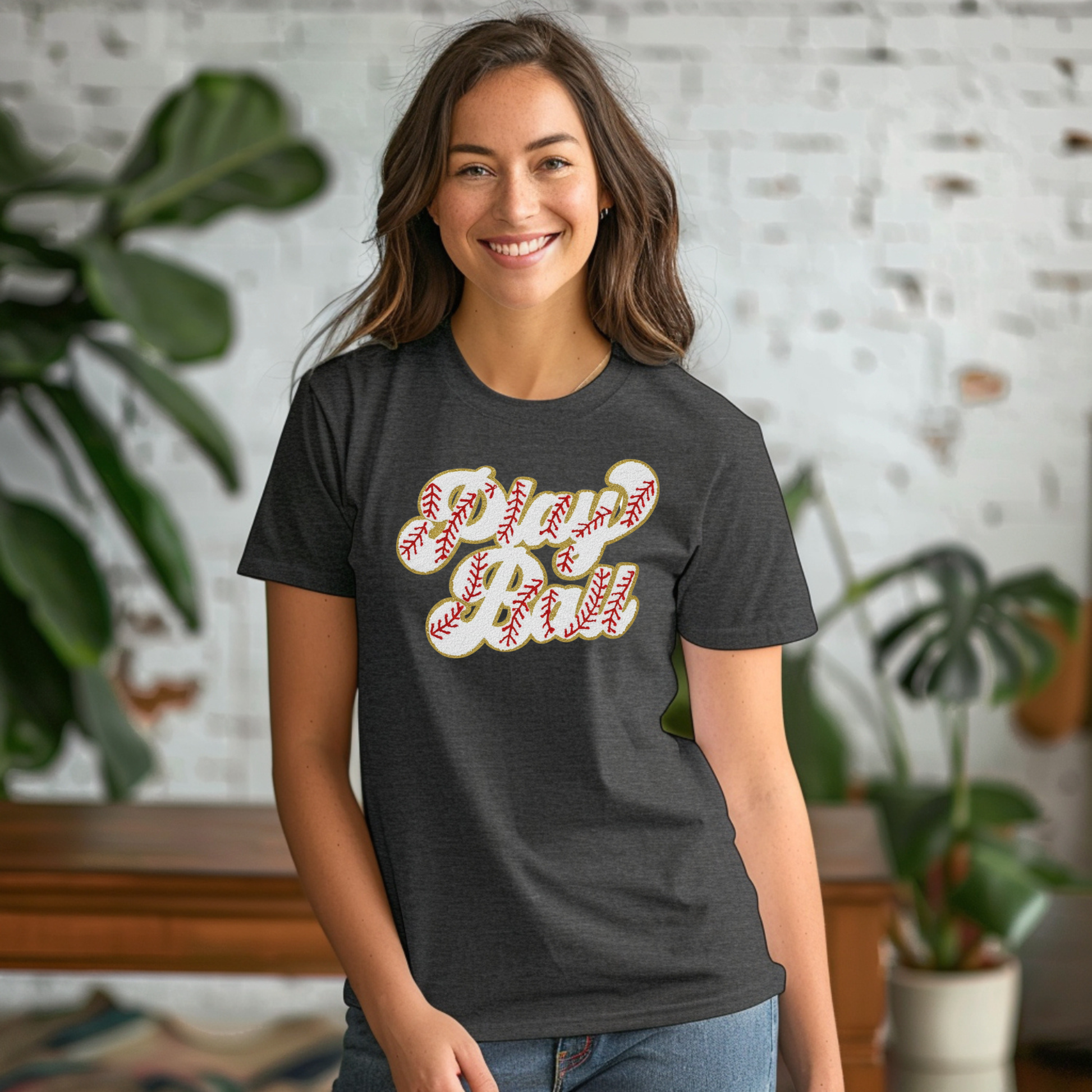 Woman wearing a dark gray t-shirt with a graphic design, standing indoors with plants in the background.