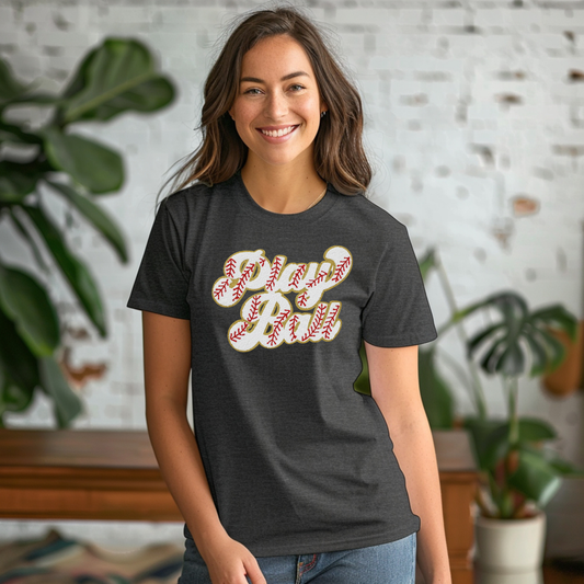 Woman wearing a dark gray t-shirt with a graphic design, standing indoors with plants in the background.