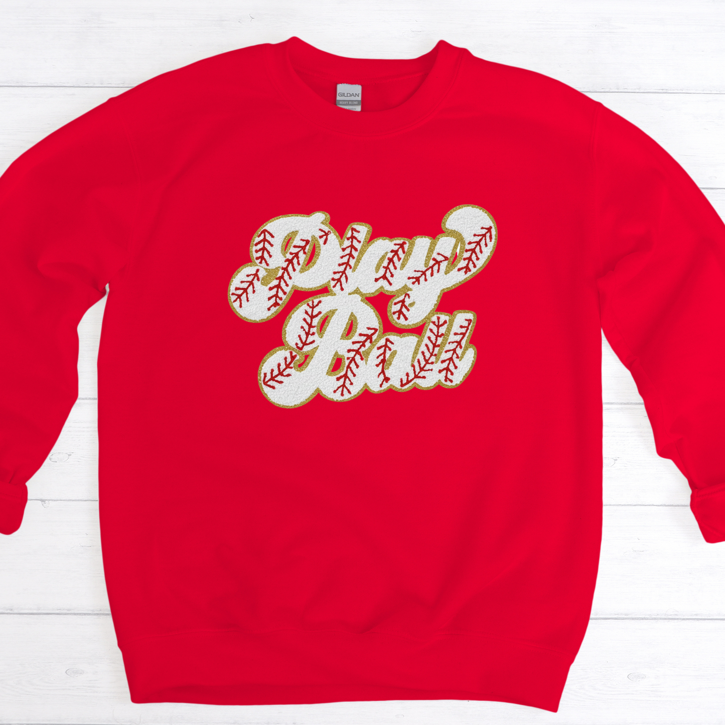 Red sweatshirt with 'Play Ball' text on a white wooden background