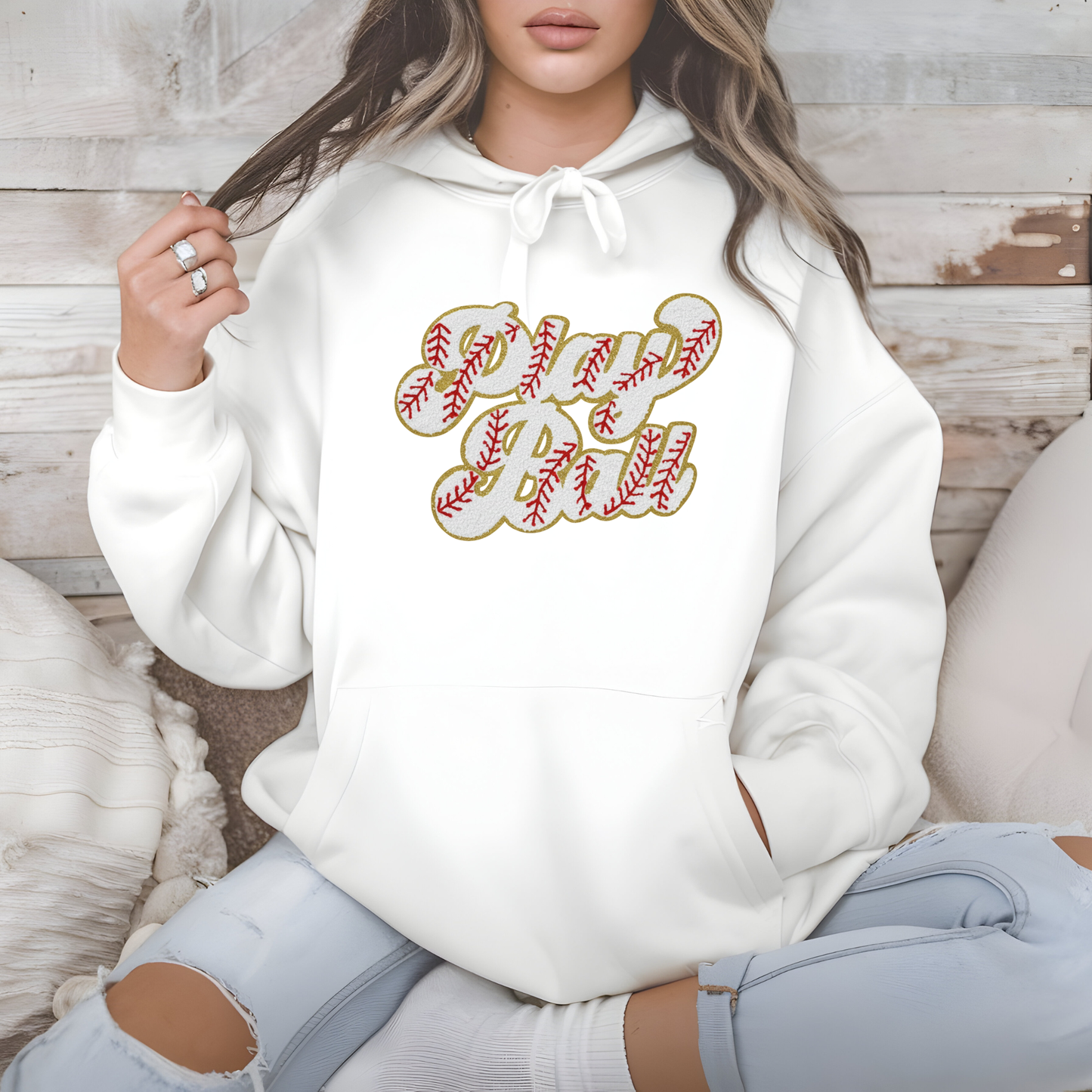Person wearing a white hoodie with a graphic design sitting on a wooden floor.