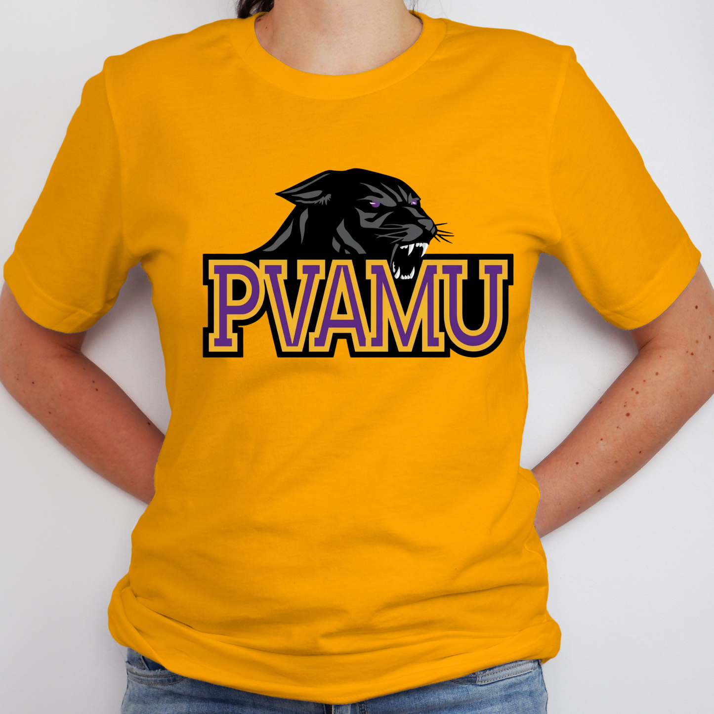 A person wearing a bright yellow short-sleeve t-shirt with a black panther graphic and the text 'PVAMU' in purple and black outlined block letters across the chest, paired with blue jeans against a plain light gray background.