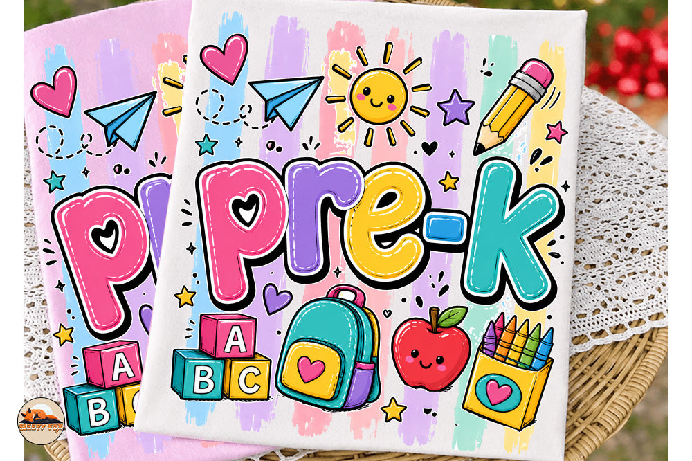 Two colorful square canvas prints featuring a playful 'pre-k' school theme with hand-drawn cartoon letters, a smiling sun, paper airplanes, stars, blocks, a backpack, an apple, and crayons, displayed on a wicker tray over a lace doily.