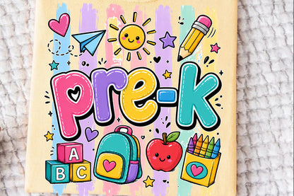 A folded pale yellow t-shirt with a colorful 'Pre-K' school supplies graphic, laid flat on a textured white blanket.
