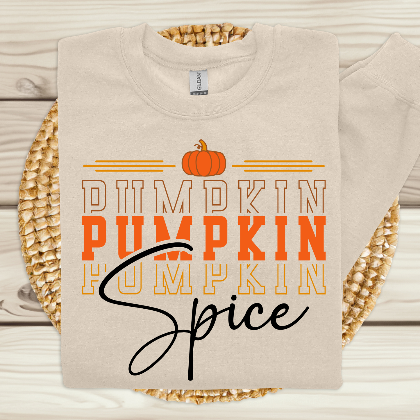 Beige sweatshirt with 'Pumpkin Spice' text and pumpkin graphic on a woven mat.