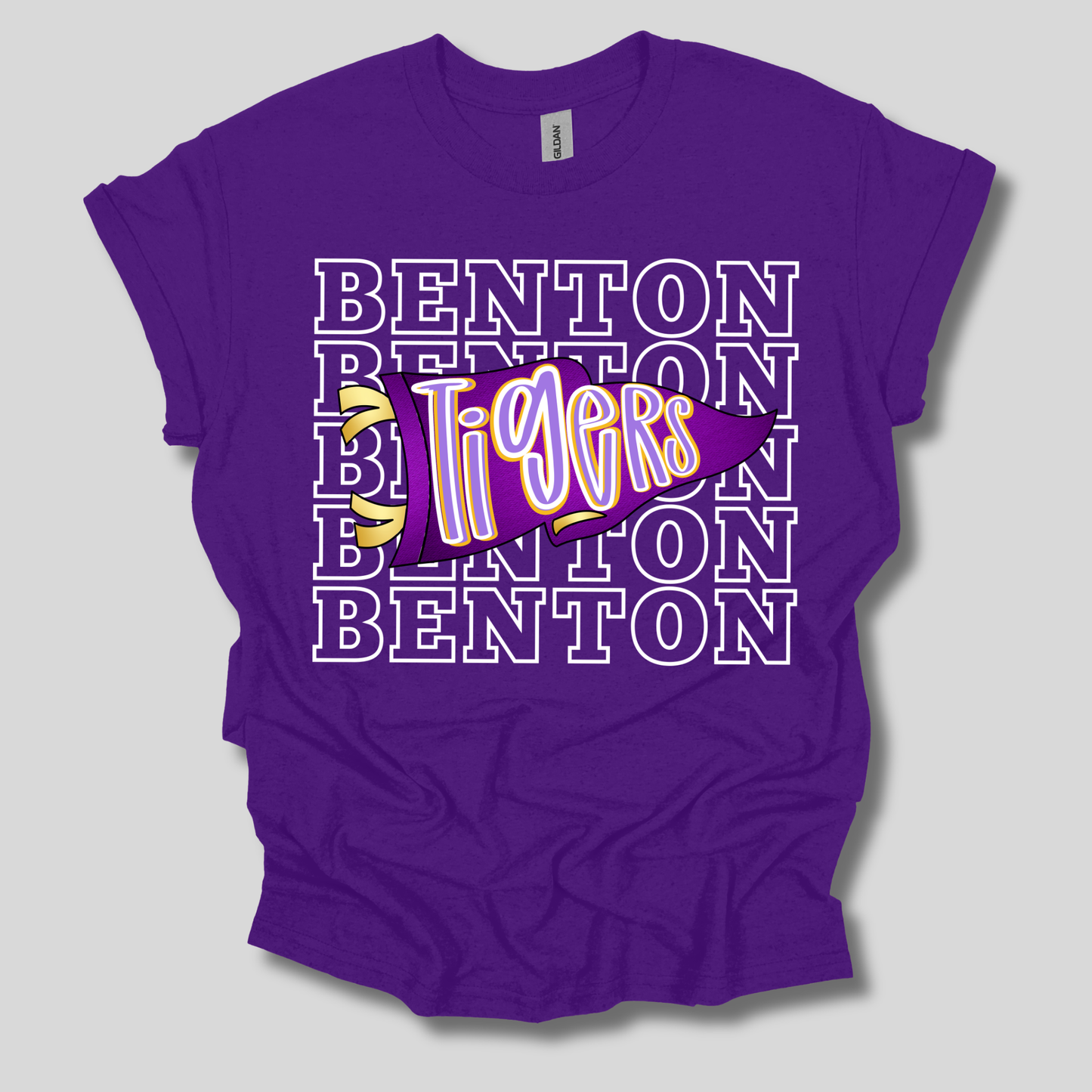 A purple short-sleeve t-shirt with a graphic design on the front. The design features the word 'BENTON' repeated in white outline letters, with a central purple banner reading 'Tigers' in stylized white and yellow lettering, accented by two small yellow tiger faces.