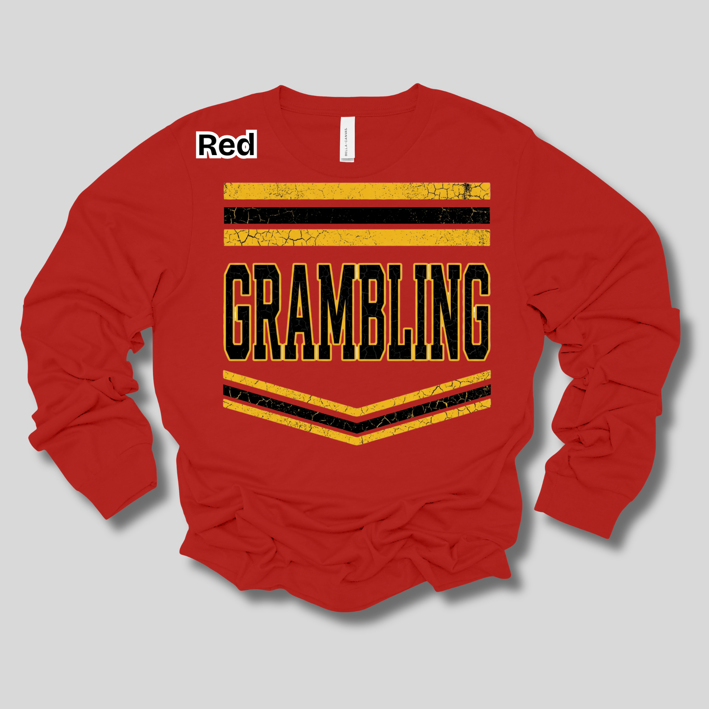 A red long-sleeve crewneck sweatshirt with a distressed graphic on the chest reading 'GRAMBLING' in black letters outlined in gold, flanked by gold and black chevron stripes. A small white label in the upper left reads 'Red'.