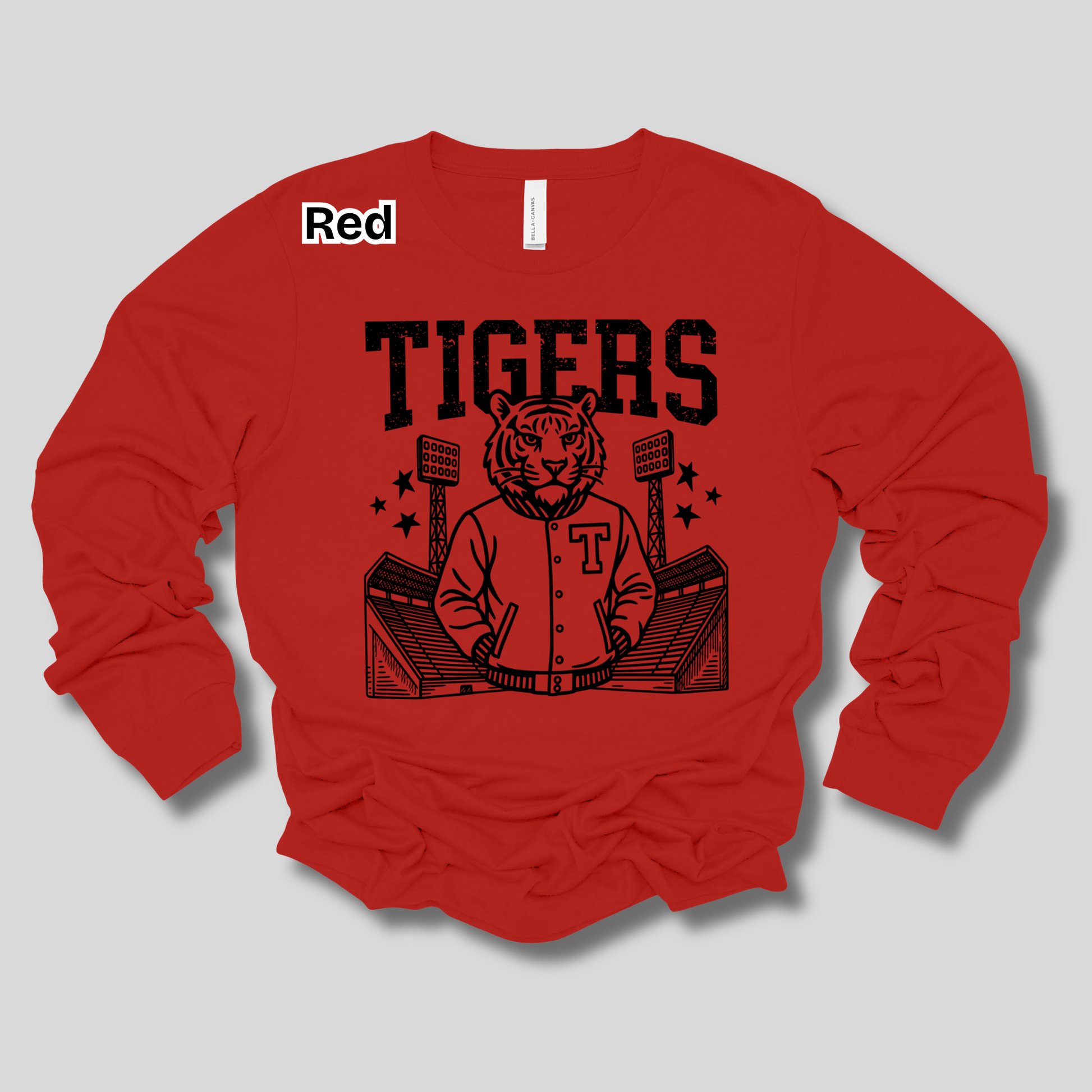 A red long-sleeve t-shirt with a black graphic of a tiger mascot in a baseball uniform holding a bat, with the word 'TIGERS' printed above. A small white label in the upper left reads 'Red'.