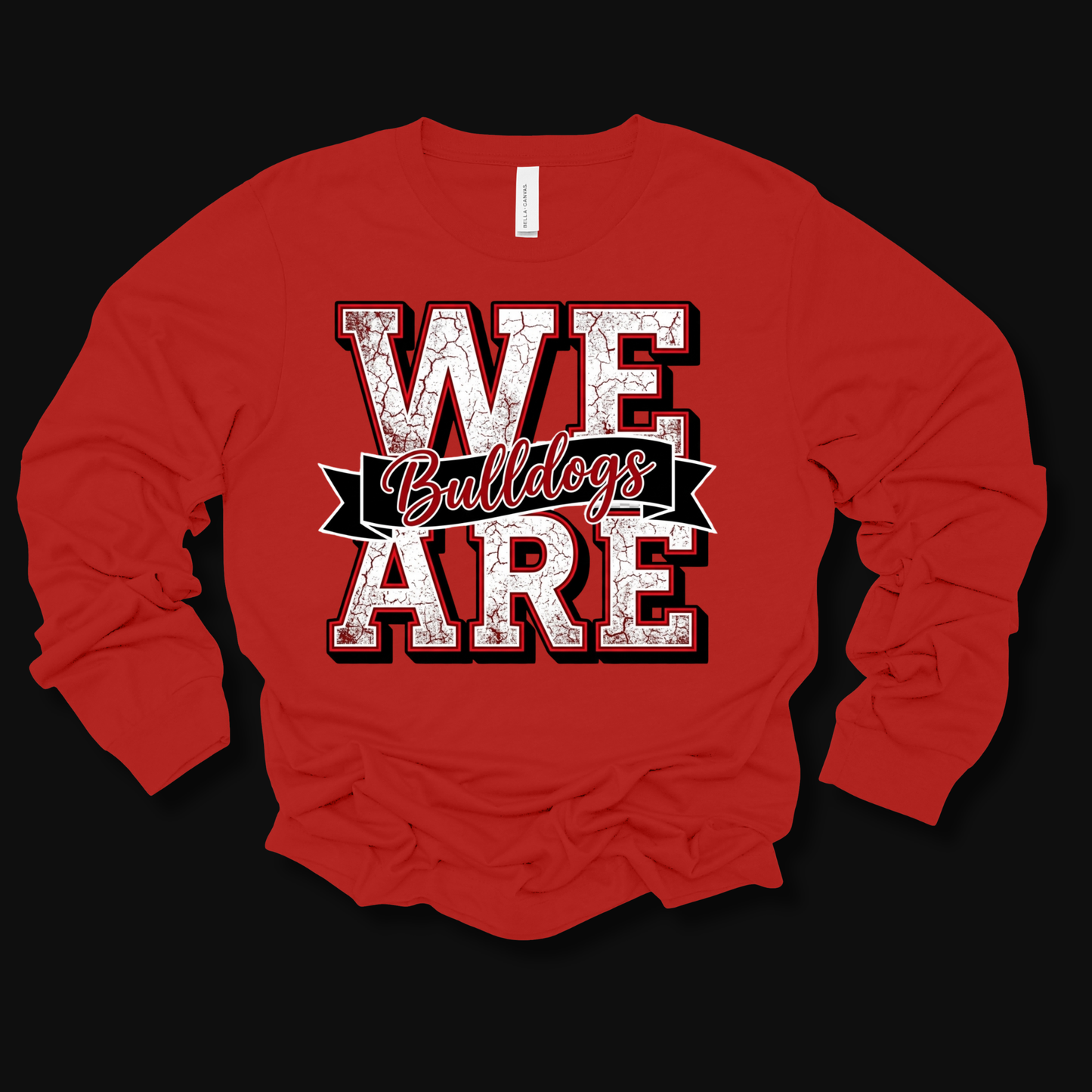 A red long-sleeve t-shirt with a distressed graphic on the front that reads 'WE ARE Bulldogs' in white and black, laid flat on a black background.