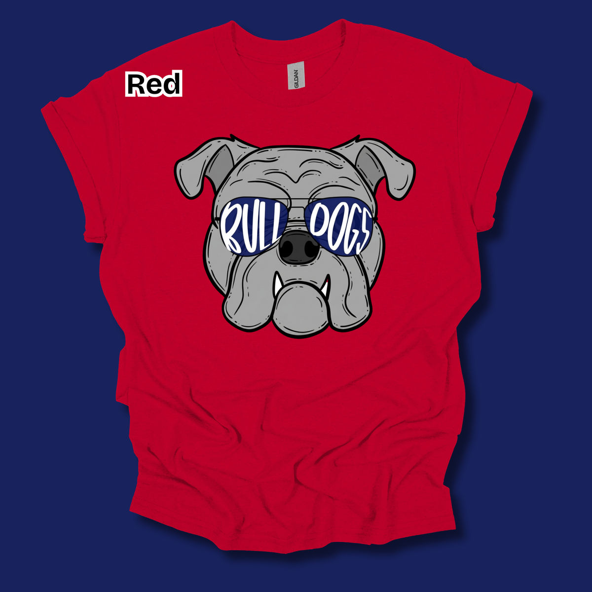 A red short-sleeve t-shirt with a graphic of a bulldog wearing blue sunglasses that say 'RULL DOGS' in white. The shirt is laid flat on a dark blue background, and the word 'Red' is printed in white on the upper left chest.