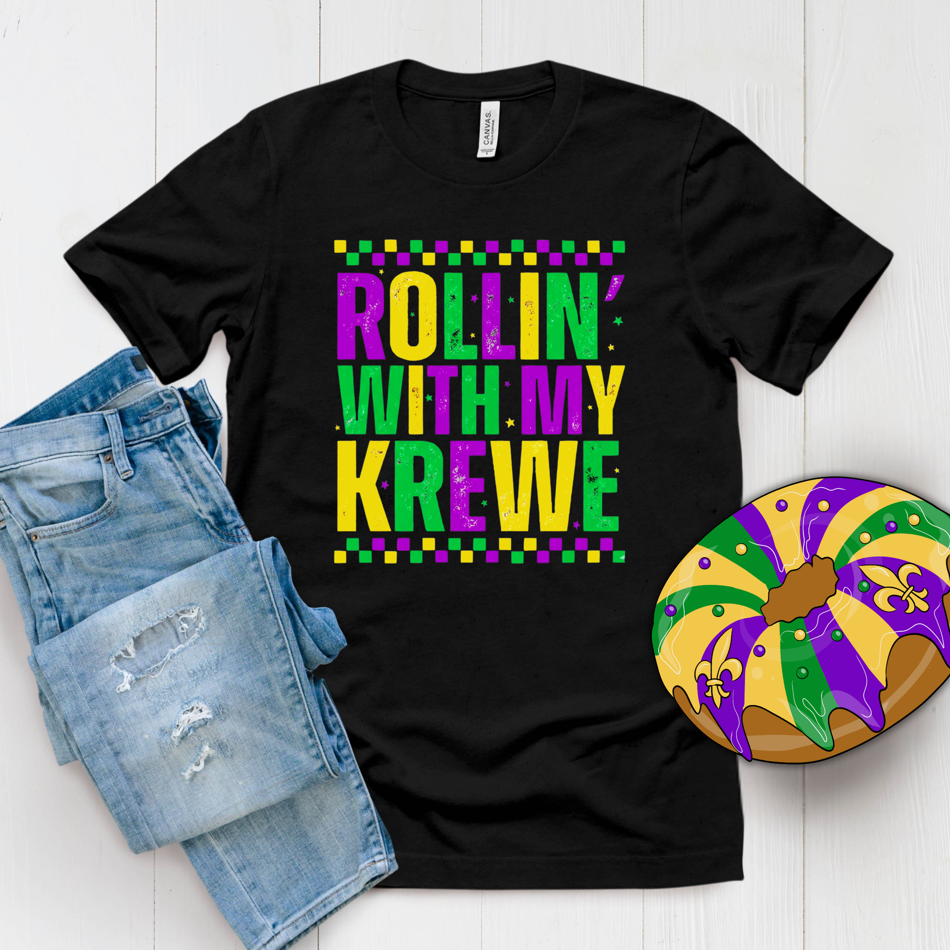 Black t-shirt with 'Rollin' with my Krewe' text, denim shorts, and Mardi Gras-themed donut on a white background