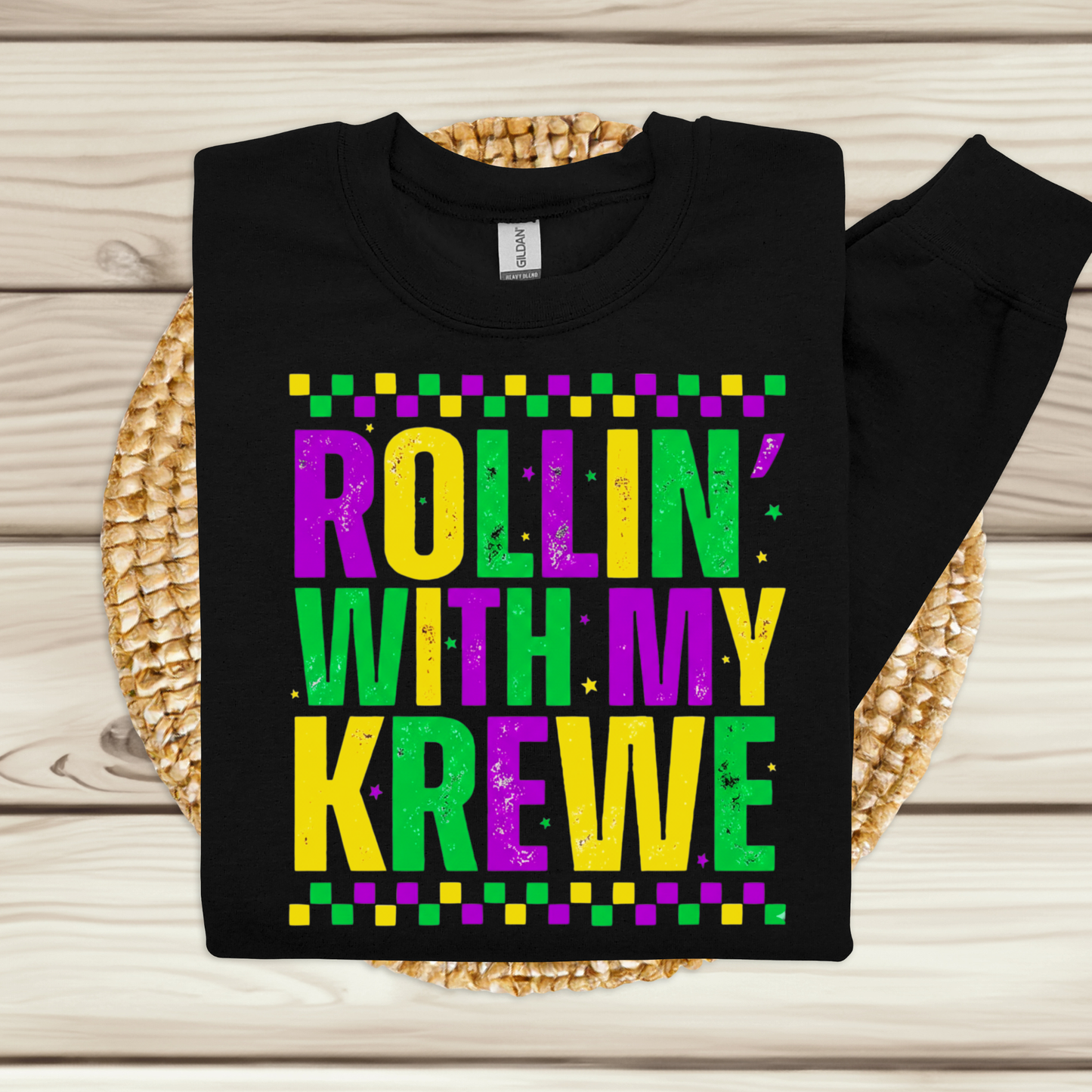 Black sweatshirt with colorful text 'Rollin' with my Krewe' on a wooden surface
