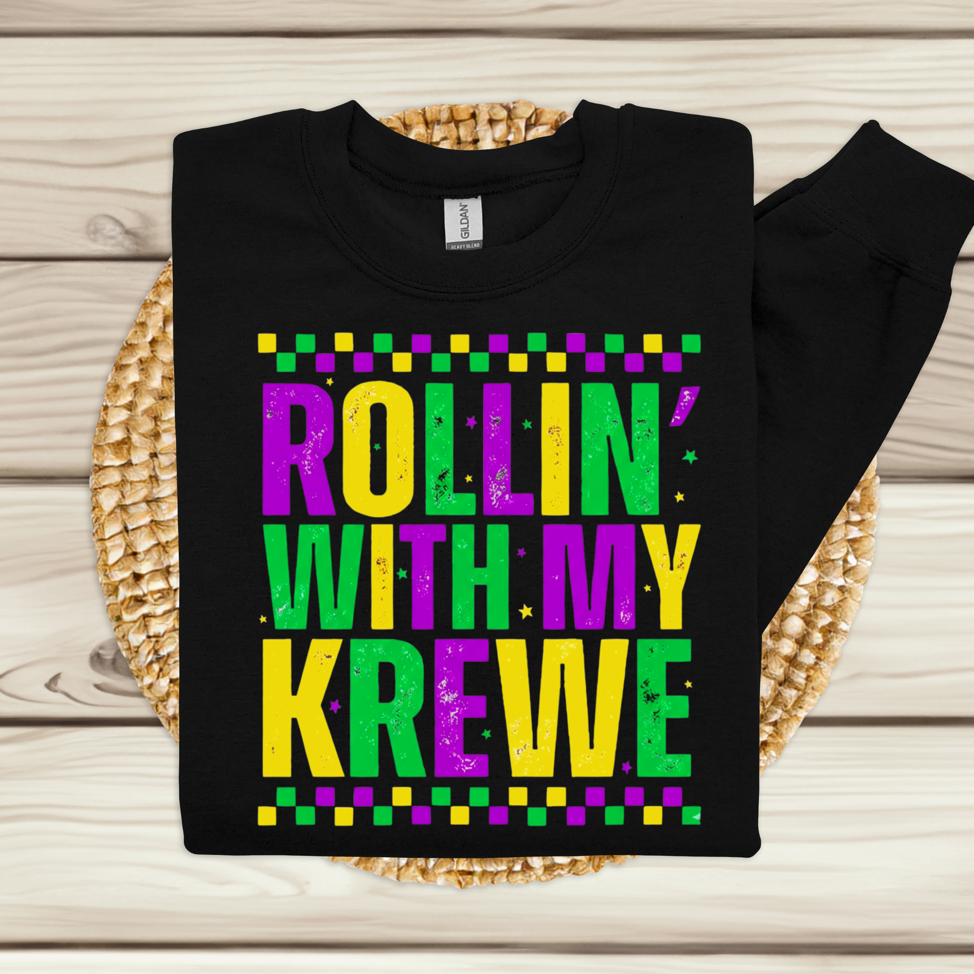 Black sweatshirt with colorful text 'Rollin' with my Krewe' on a wooden surface