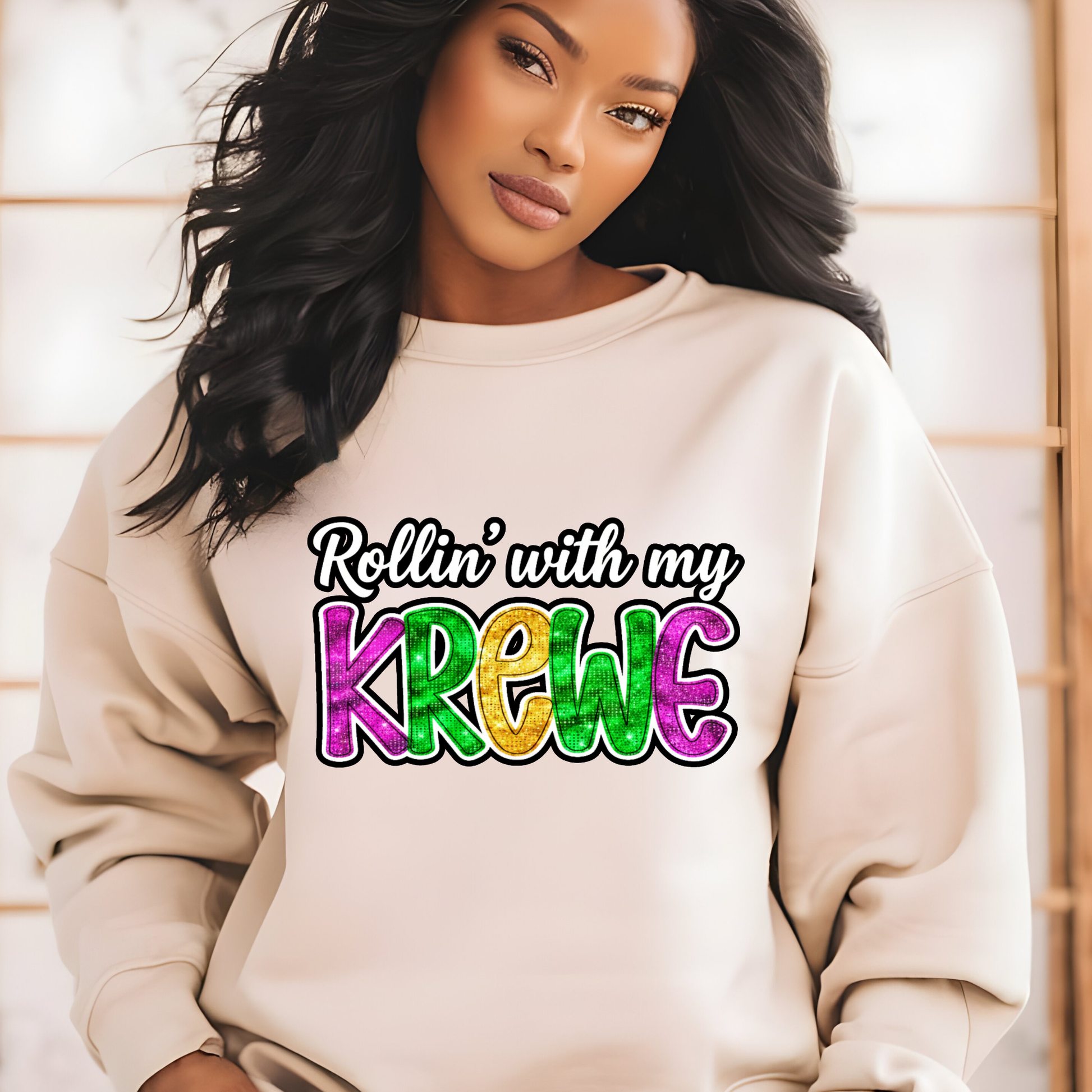 Woman wearing a beige sweatshirt with 'Rollin' with my Krewe' text in colorful letters.