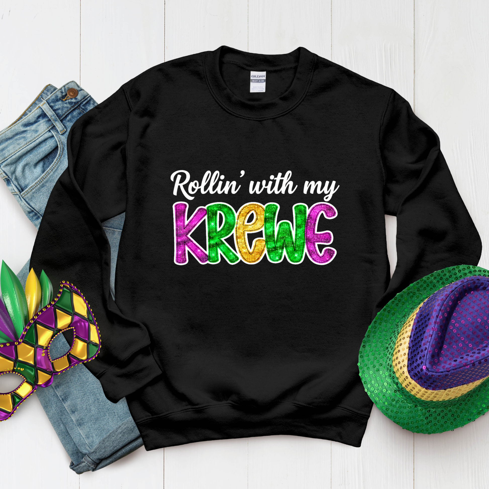 Black sweatshirt with 'Rollin' with my Krewe' text, surrounded by Mardi Gras accessories on a white background.