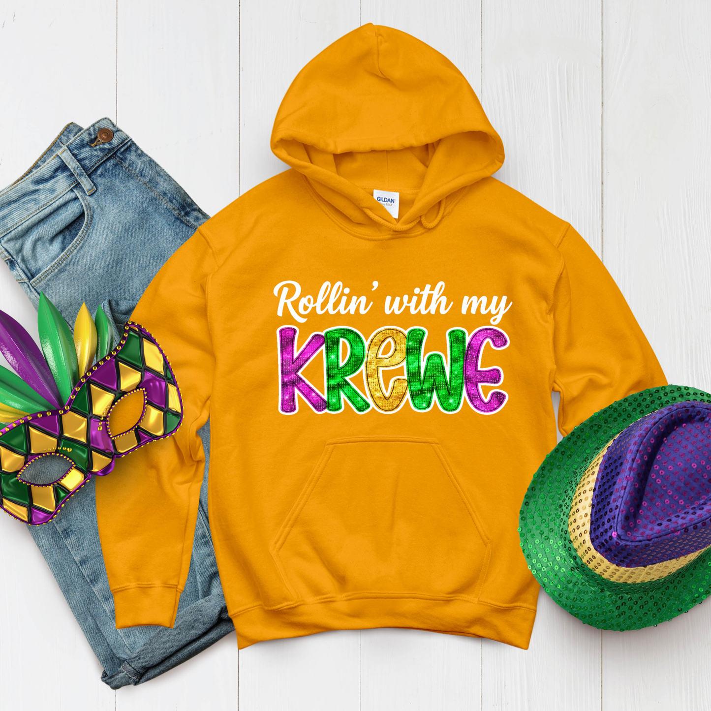 Orange hoodie with 'Rollin' with my Krewe' text, jeans, mask, and hat on a white background