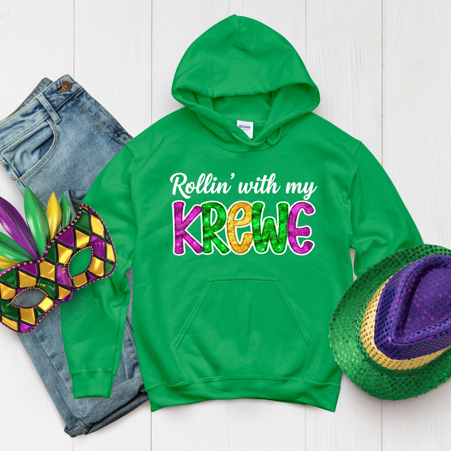Green hoodie with 'Rollin' with my Krewe' text, jeans, and Mardi Gras mask on a white background