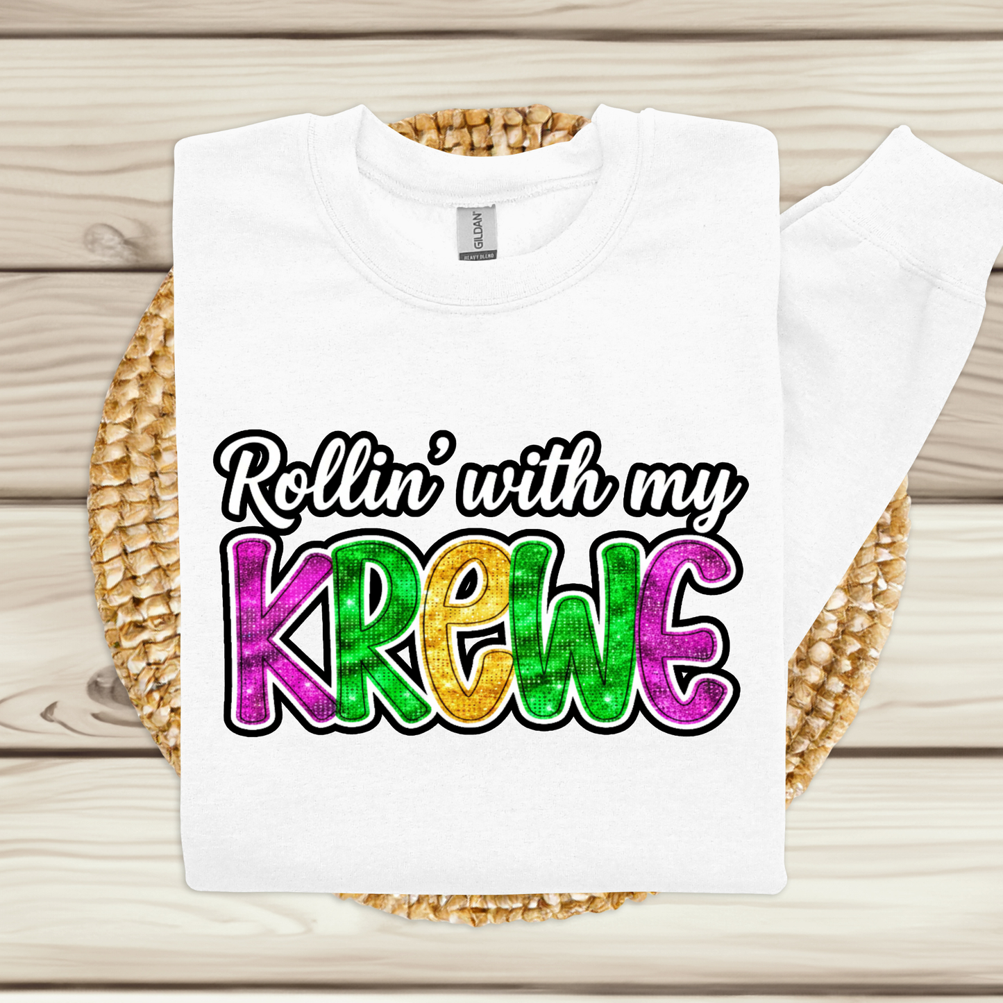 White t-shirt with colorful text 'Rollin' with my KREWC' on a woven mat.