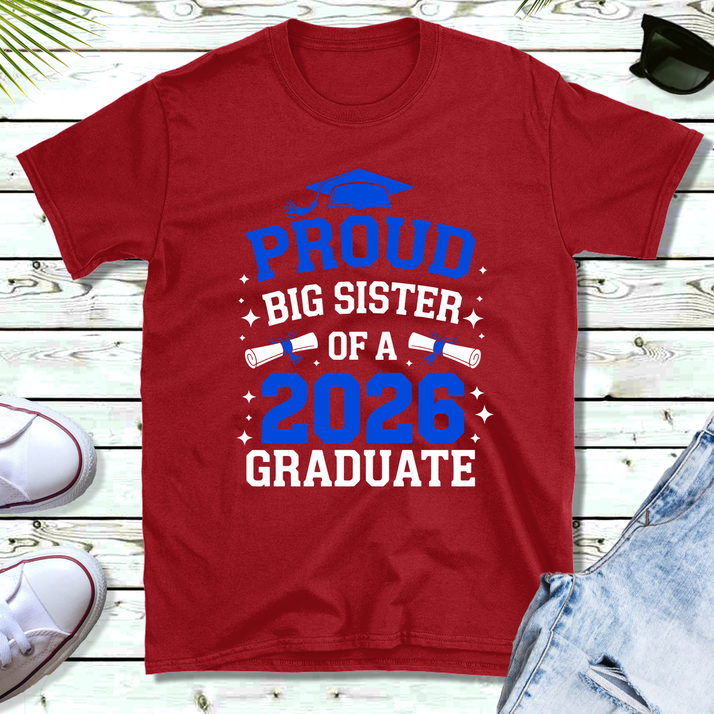 Red t-shirt with 'Proud Big Sister of a 2026 Graduate' text on a wooden surface.