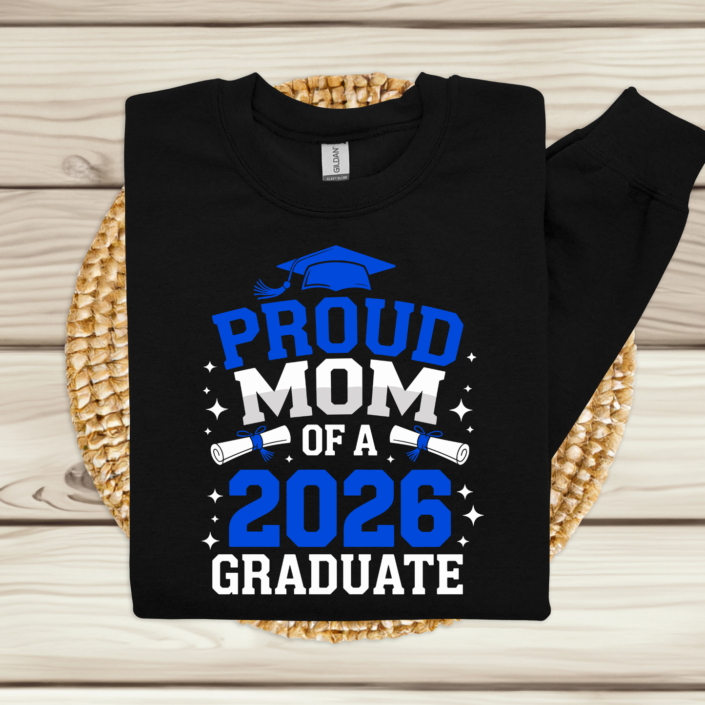 Black sweatshirt with 'Proud Mom of a 2026 Graduate' text on a woven mat.