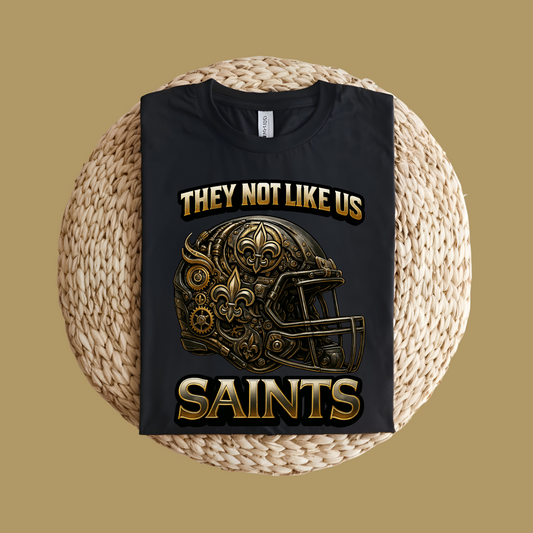 Black t-shirt with gold and white text  and graphics on a woven surface Saints Mascot Shirt - Saints They Not Like Us Game Day Football Tee