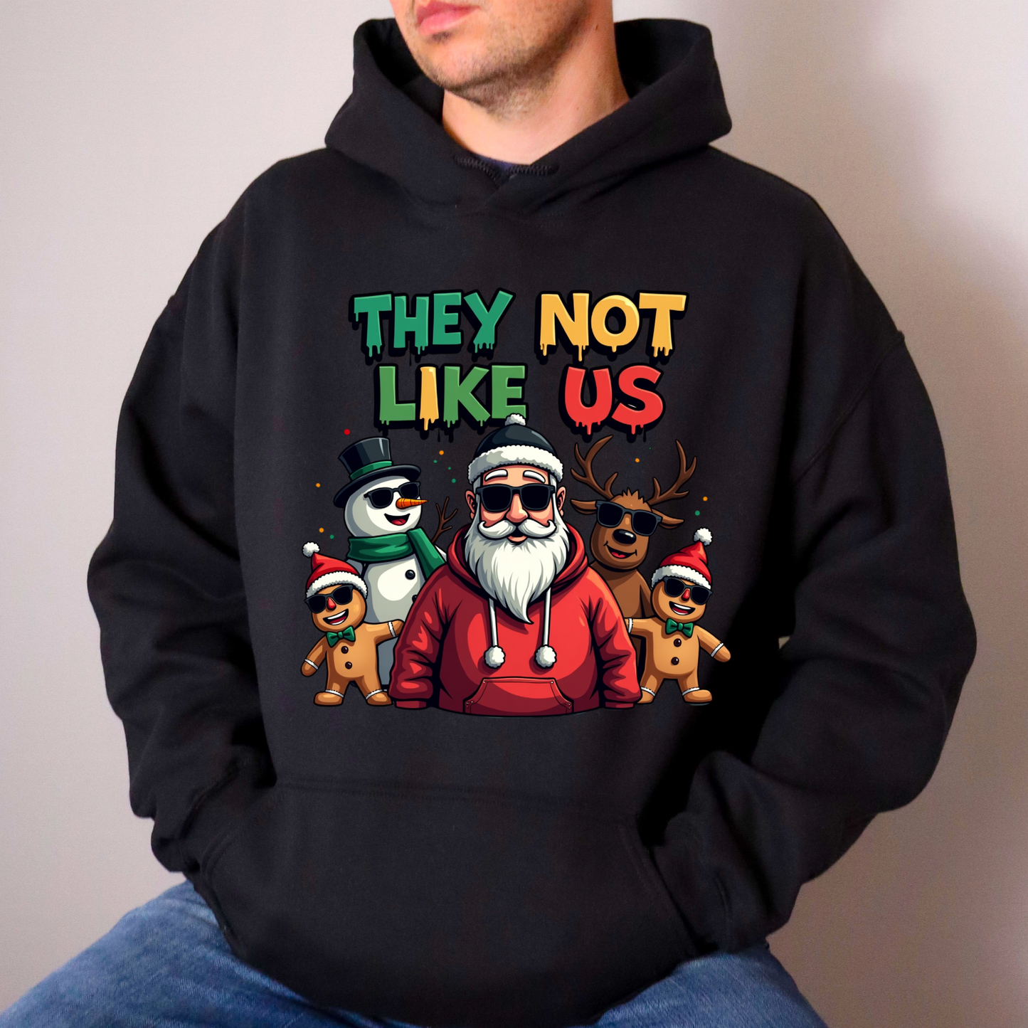 Person wearing a black hoodie with a colorful graphic and text on a plain background