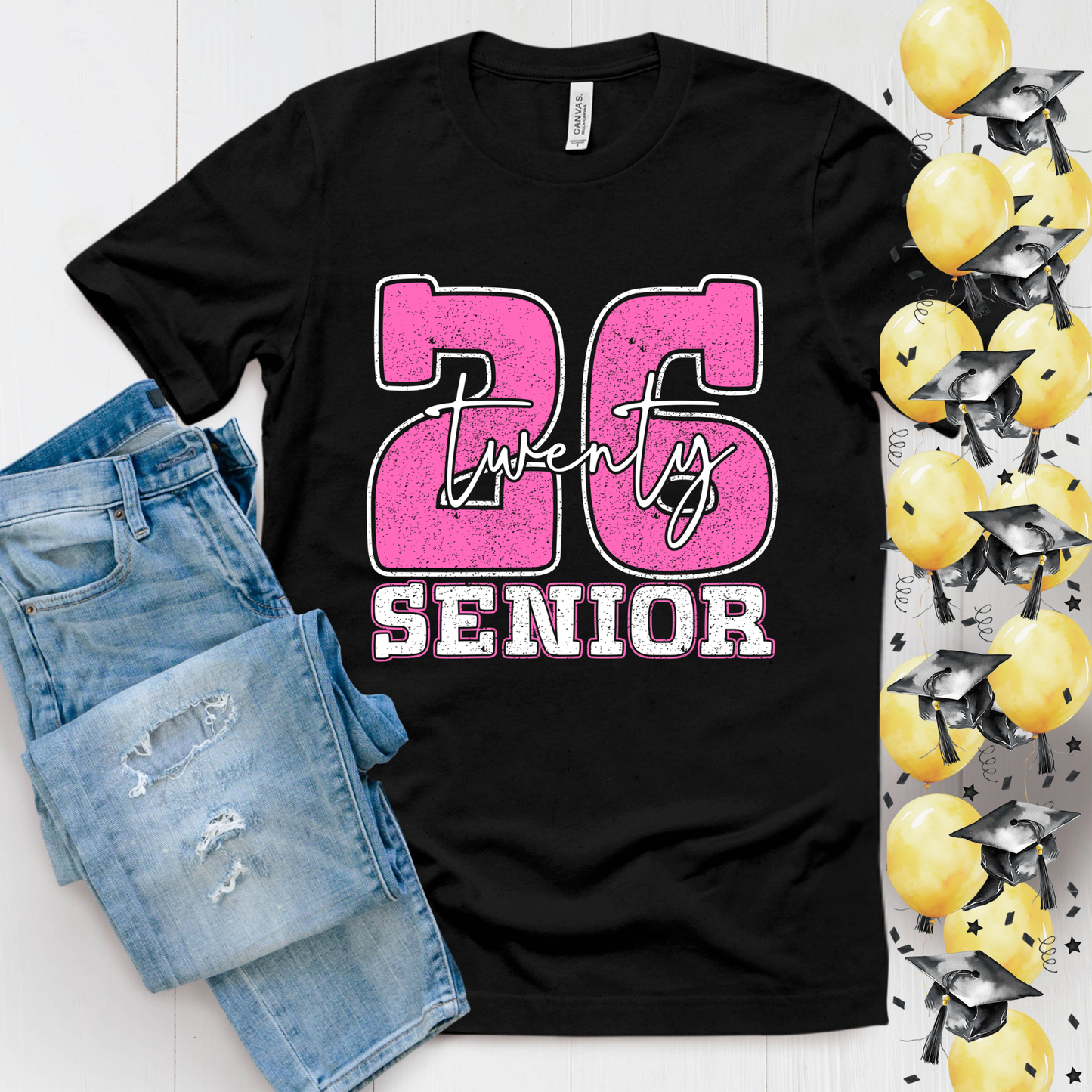 Black t-shirt with pink and white '26 Senior' design, paired with denim shorts and graduation caps and diplomas on a white background.