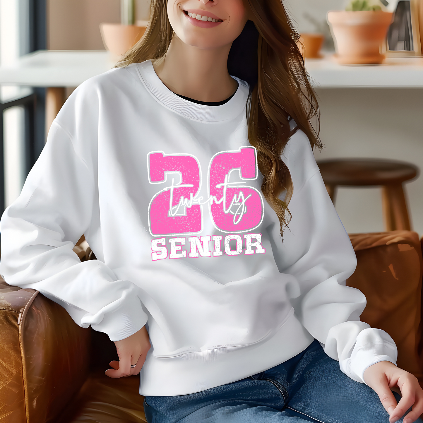 Person wearing a white sweatshirt with pink text sitting on a couch.