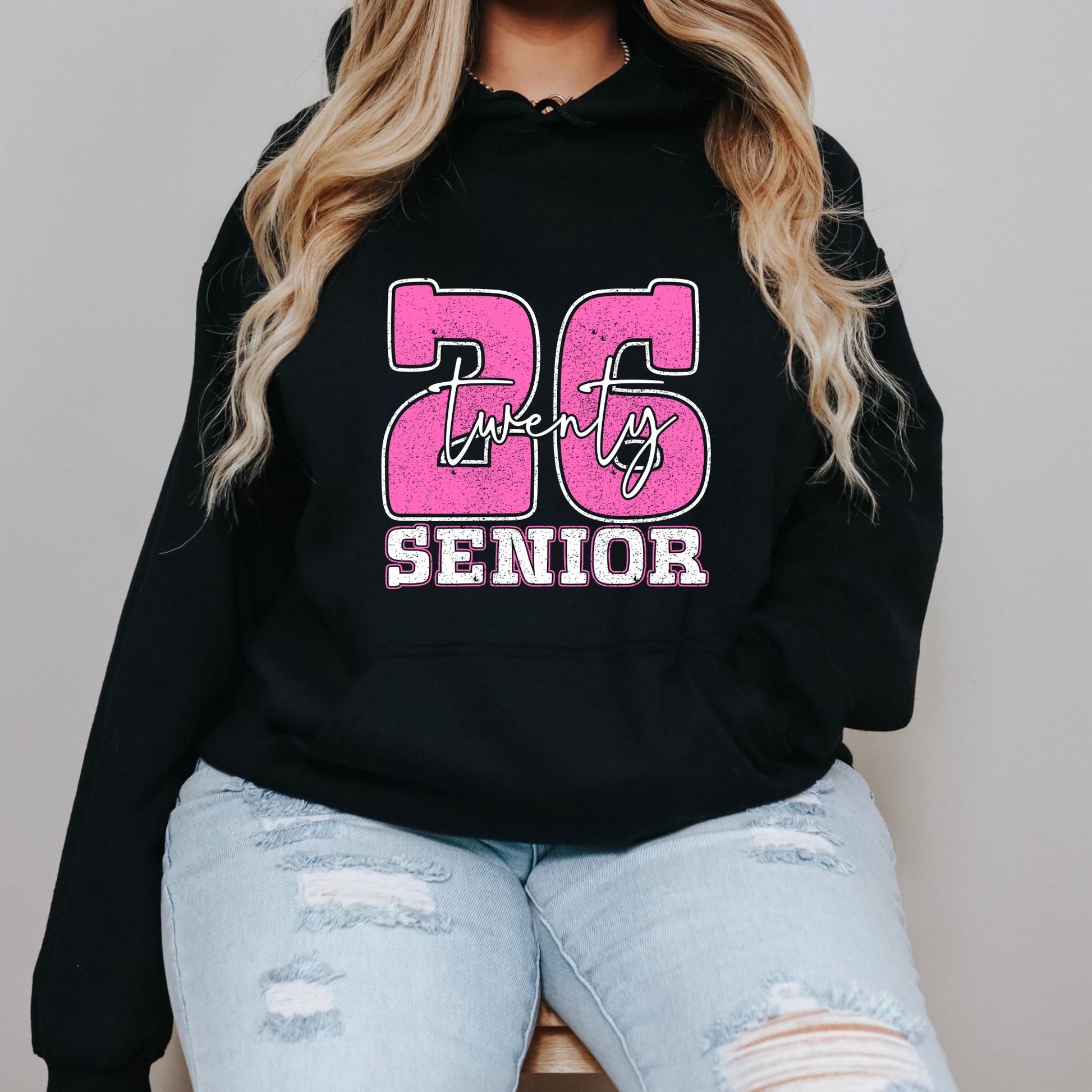Person wearing a black hoodie with pink and white text on a plain background Senior 2026 T-Shirt - Graduating Senior - Customizable Class of 2026 Shirt