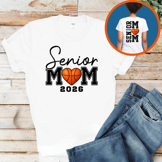 White t-shirt with 'Senior Mom 2026' design on a wooden surface with jeans.