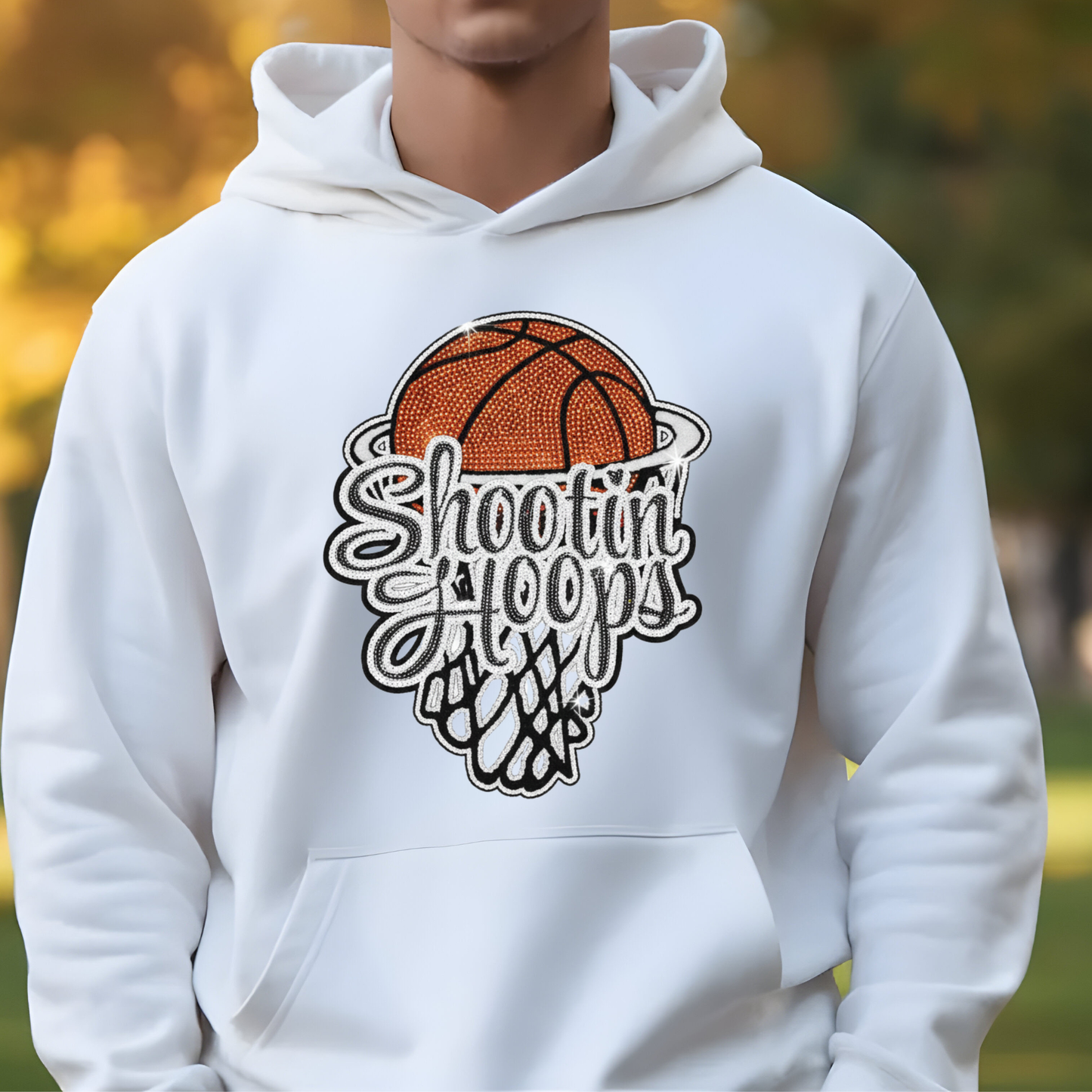 White hoodie with basketball graphic and 'Shooting Hoops' text, person wearing it outdoors.