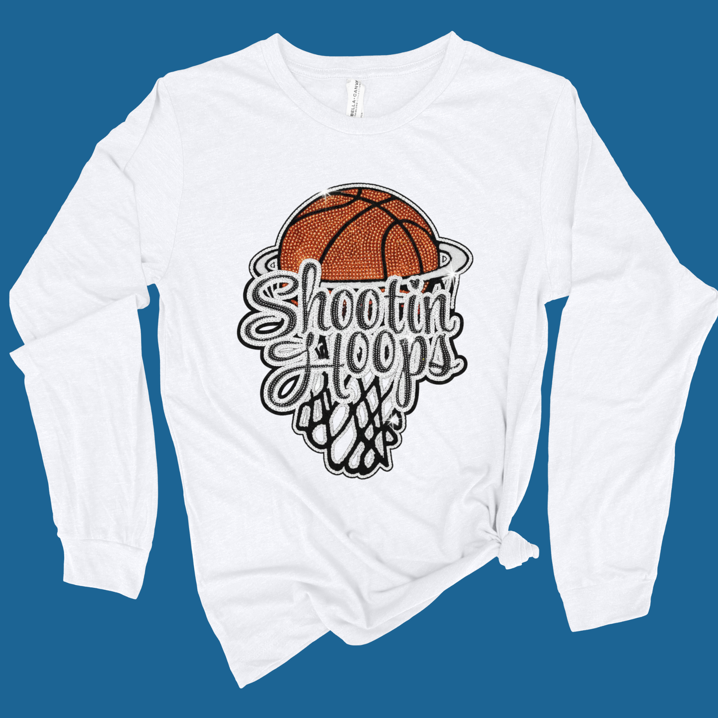 White long-sleeve shirt with a basketball graphic and 'Shootin' Hoops' text on a blue background