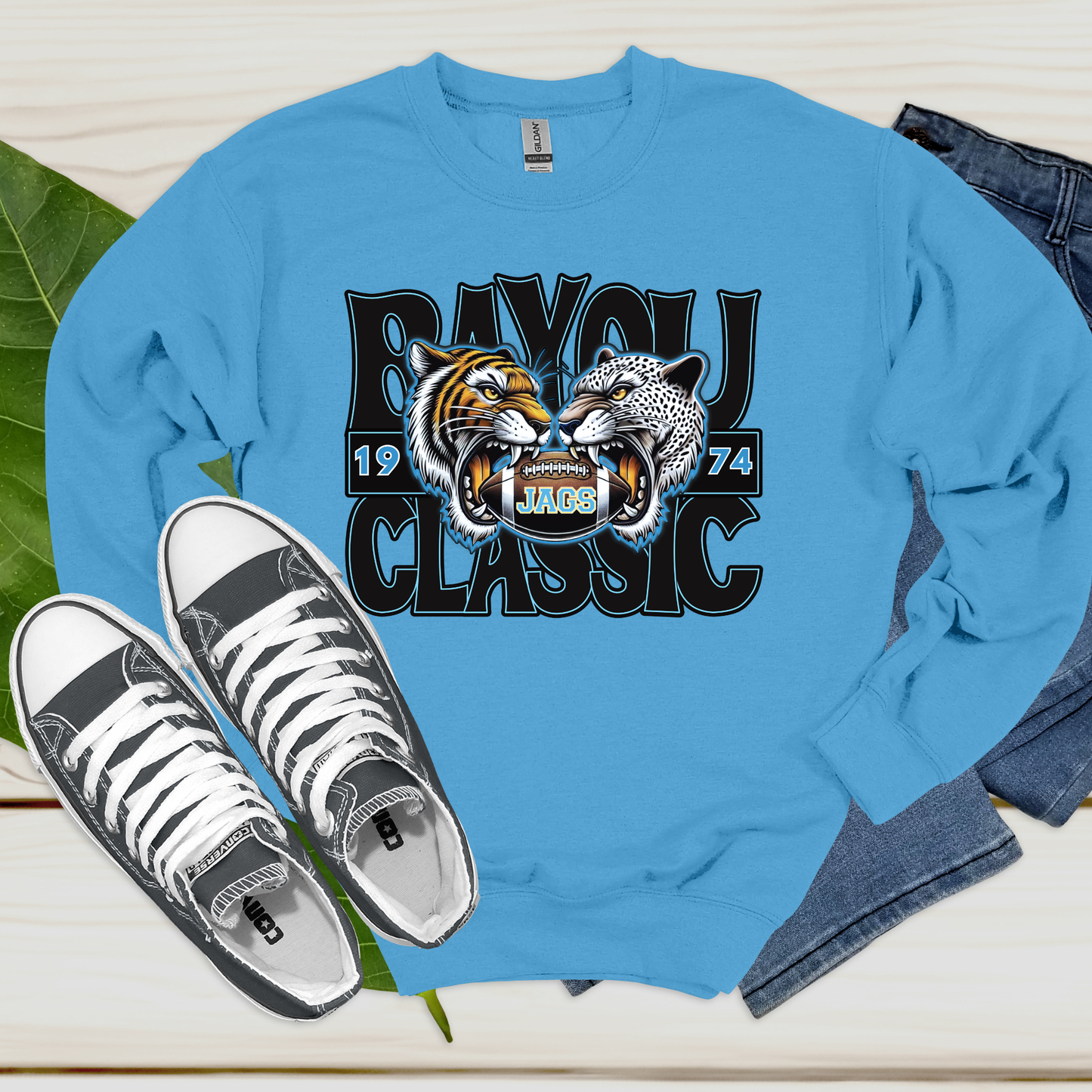 Blue sweatshirt with tiger and jaguar design and text, paired with white sneakers on a light background.