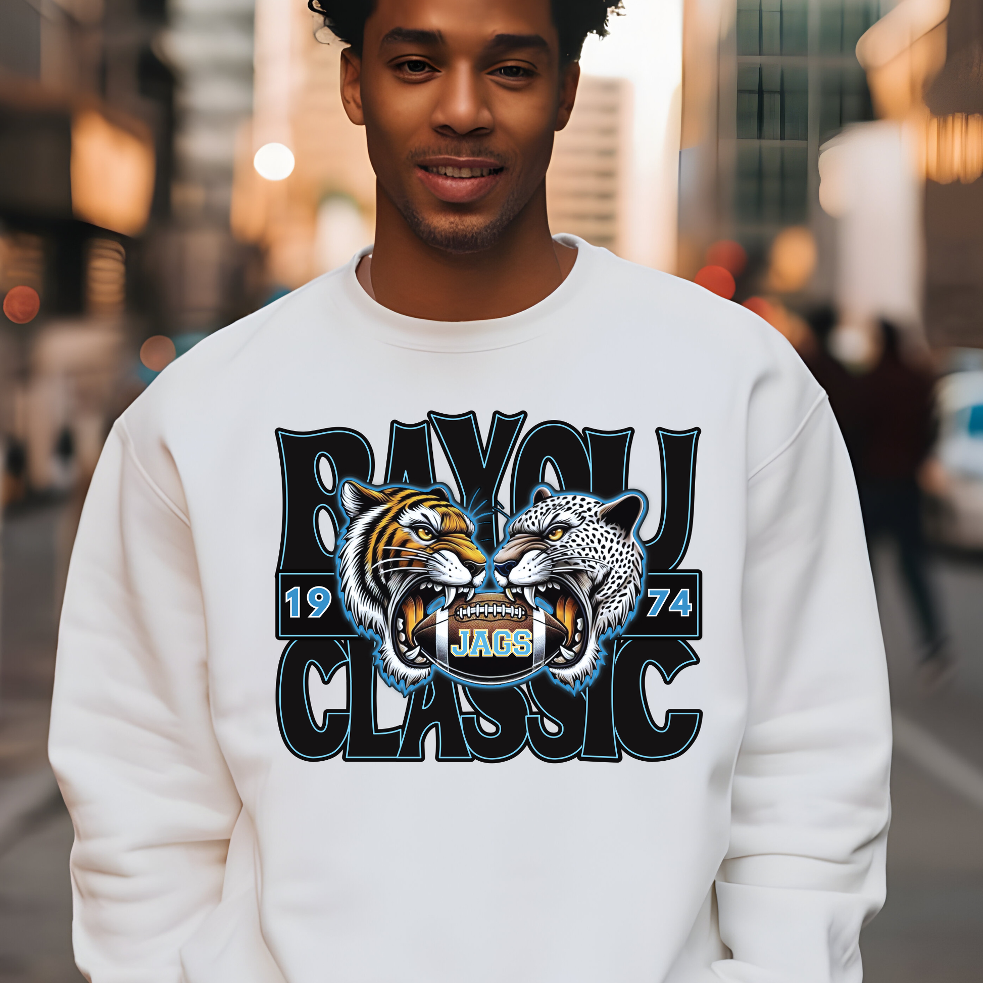 Man wearing a white sweatshirt with a graphic design of two roaring animals and text on a city street background.  Southern Jags Bayou Classic Apparel - Tailgating T-Shirt, Hoodie & Sweater