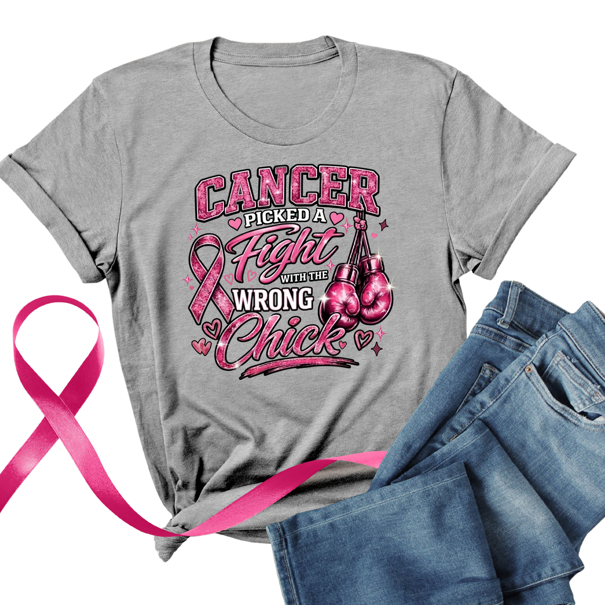 A heather gray short-sleeve graphic T-shirt laid flat with blue jeans beside it and a bright pink ribbon across the lower left. The shirt features a large front print of a Black woman in pink boxing gear with the text 'Cancer Messed With The Wrong Queen' and pink boxing gloves and a pink ribbon.