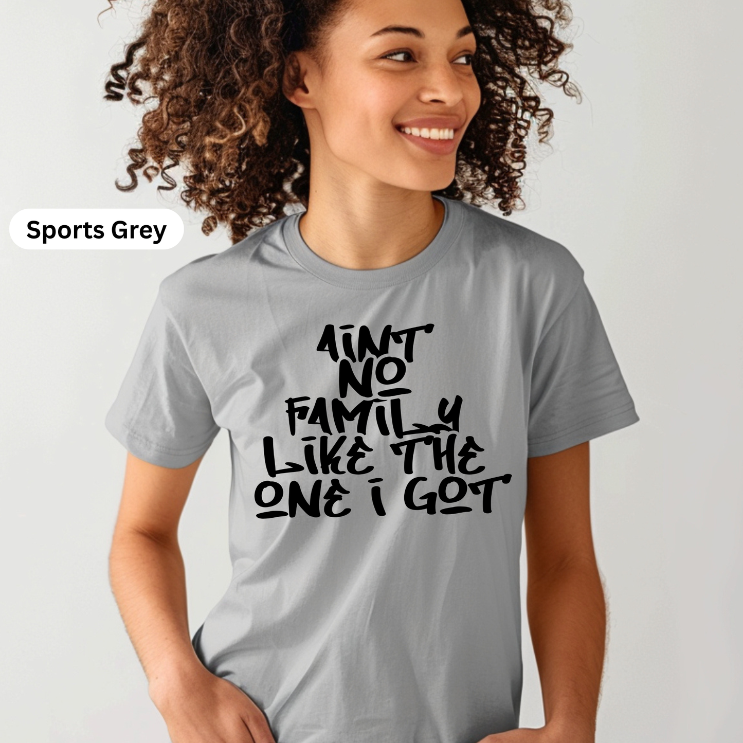 Person wearing a gray t-shirt with text, standing against a plain background