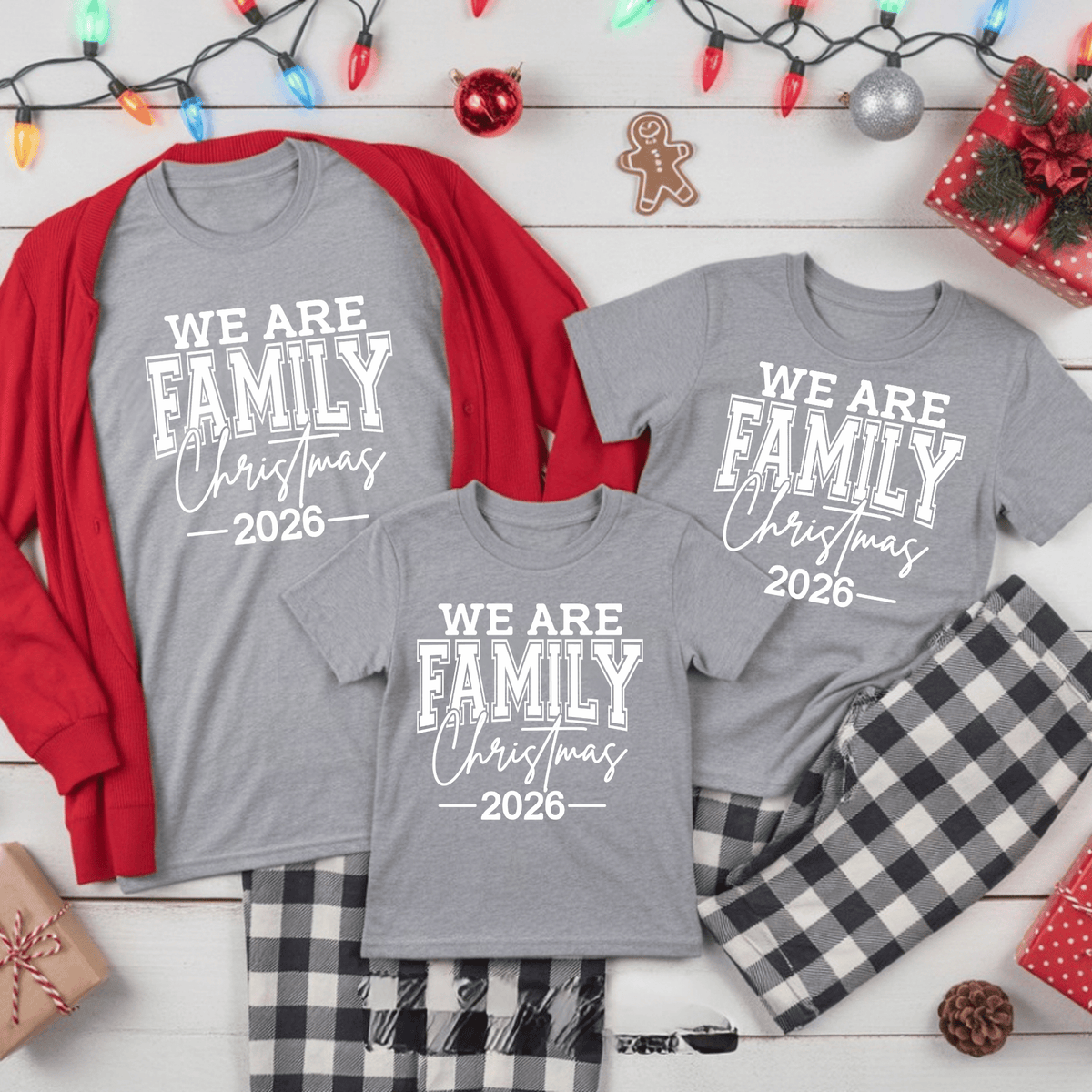 Set of five black matching family t-shirts printed with white 'We Are Family Christmas 2026' collegiate typography on a wooden backdrop.