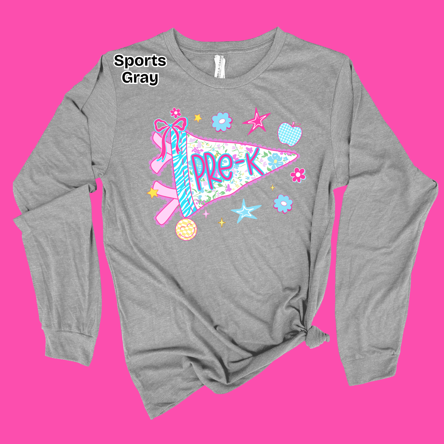 A heather gray long-sleeve t-shirt with a distressed graphic of a pink and blue pennant flag that reads 'PRE-K' surrounded by stars, flowers, and a pink ribbon. The shirt is displayed on a solid bright pink background with a 'Sports Gray' text overlay near the collar.