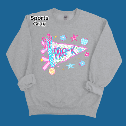 A heather gray crewneck sweatshirt with a colorful 'Pre-K' sports pennant graphic on the front, displayed against a solid blue background. The text 'Sports Gray' is printed in black near the upper left chest area.