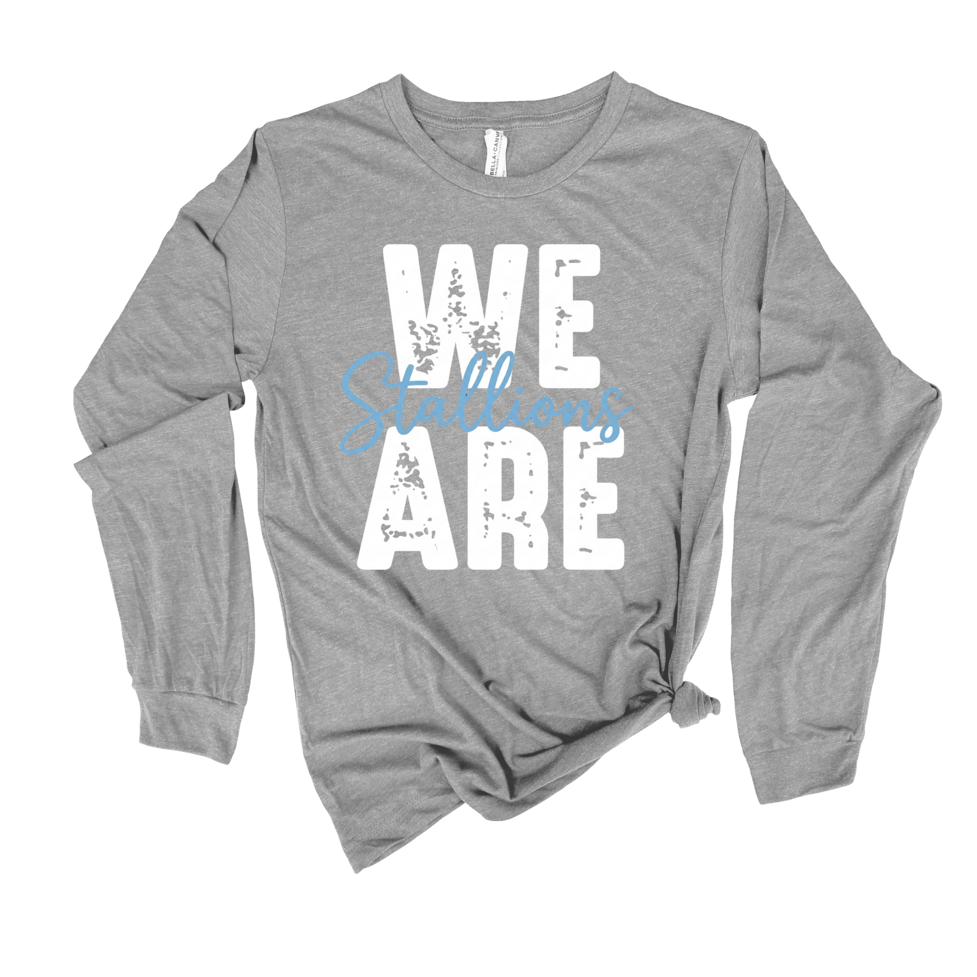 A heather gray long-sleeve t-shirt with a distressed graphic print reading 'WE ARE' in white, overlaid with the word 'Stallions' in light blue script. The shirt is styled with a knot at the bottom hem and is photographed flat against a white background.