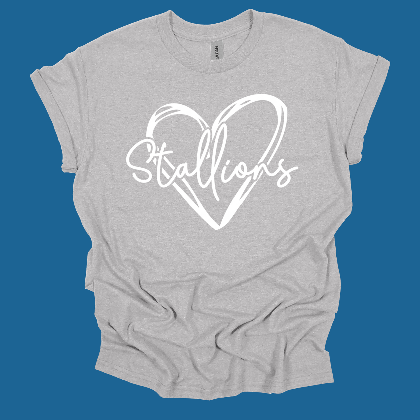 A light heather gray t-shirt with a white graphic print of a heart and the word 'Stallions' in script, displayed against a solid blue background.