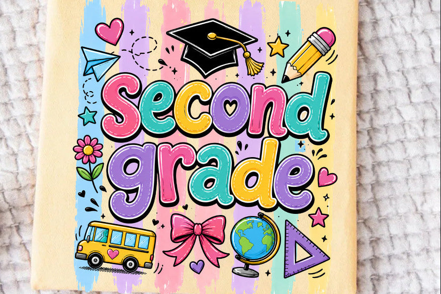 A pale yellow t-shirt featuring a colorful 'Second Grade' graphic with school-themed doodles like a graduation cap, pencil, bus, globe, and stars, laid flat on a textured white blanket.
